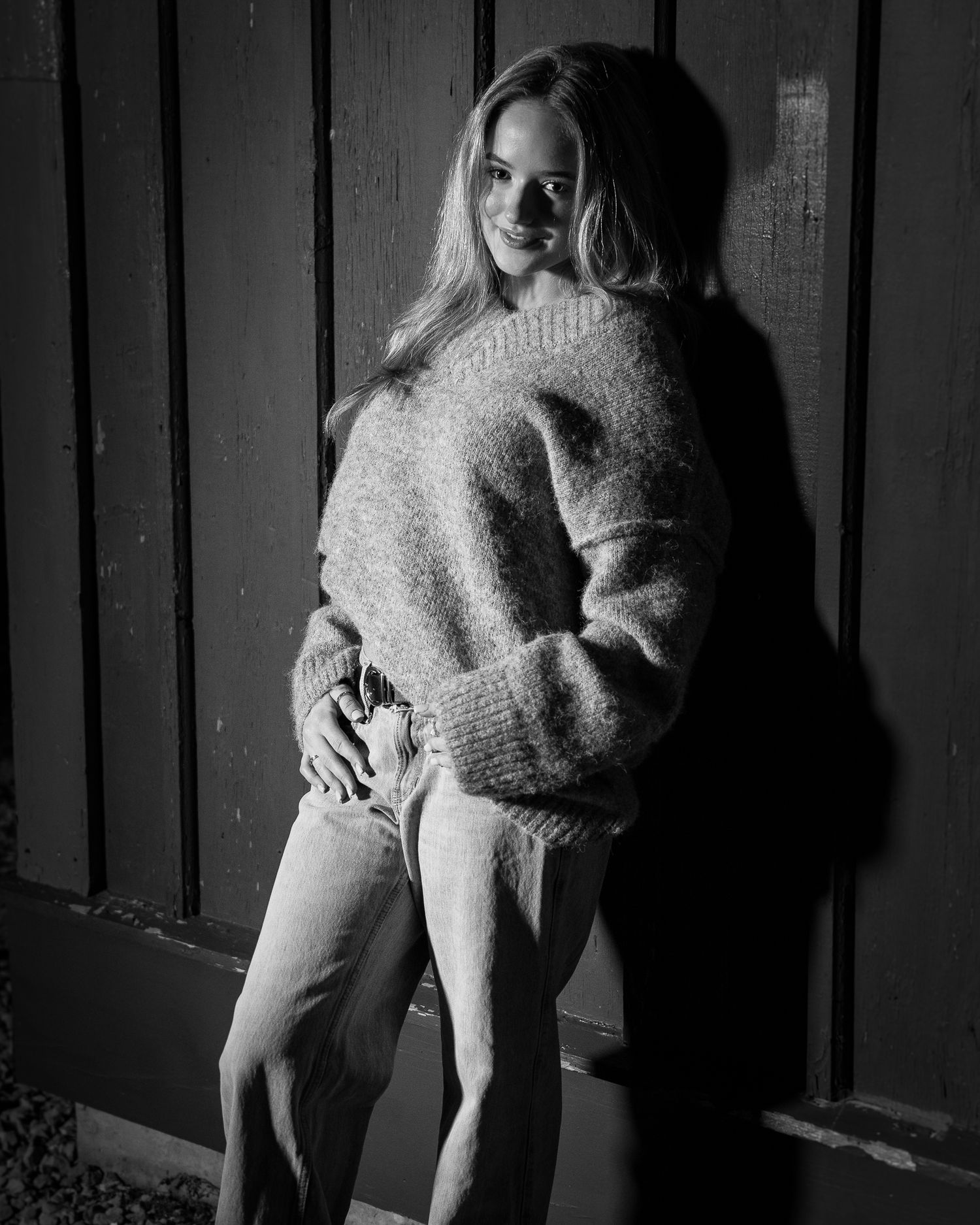 Artistic black and white portrait series featuring person in oversized sweater against dark background.