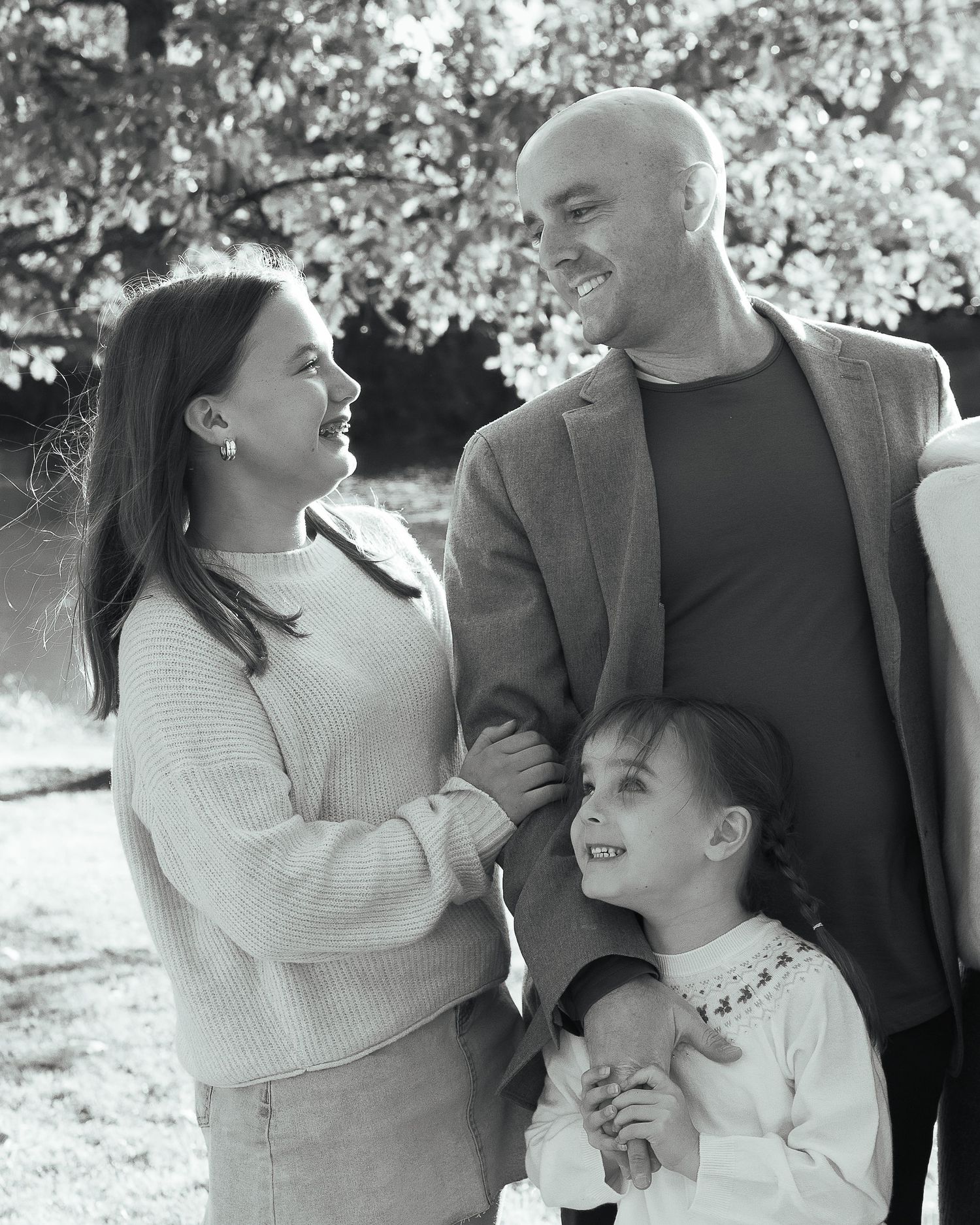 Family enjoying playful moments together outdoors in casual sweaters.