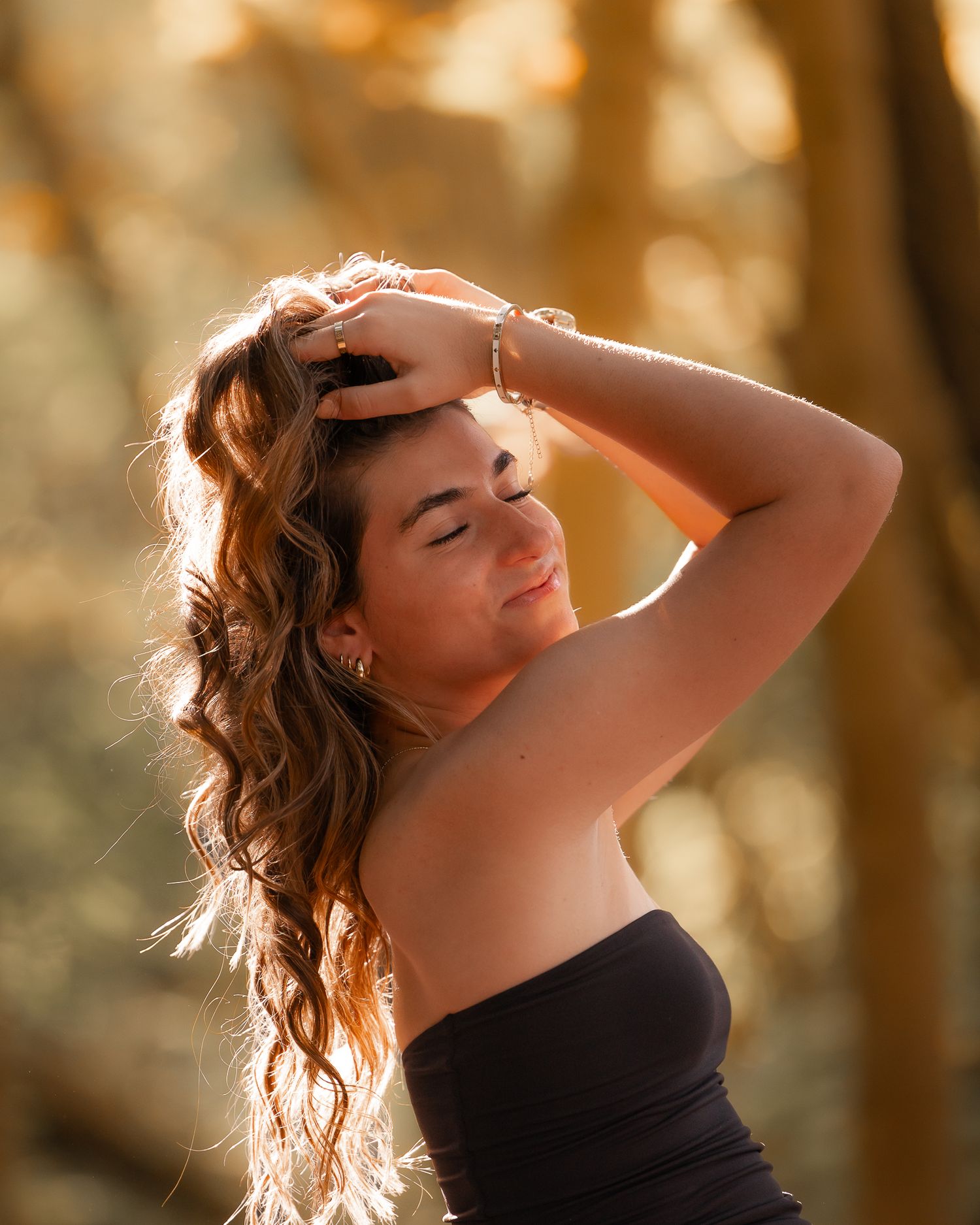 Artistic backlit portrait with golden sunlight filtering through trees.