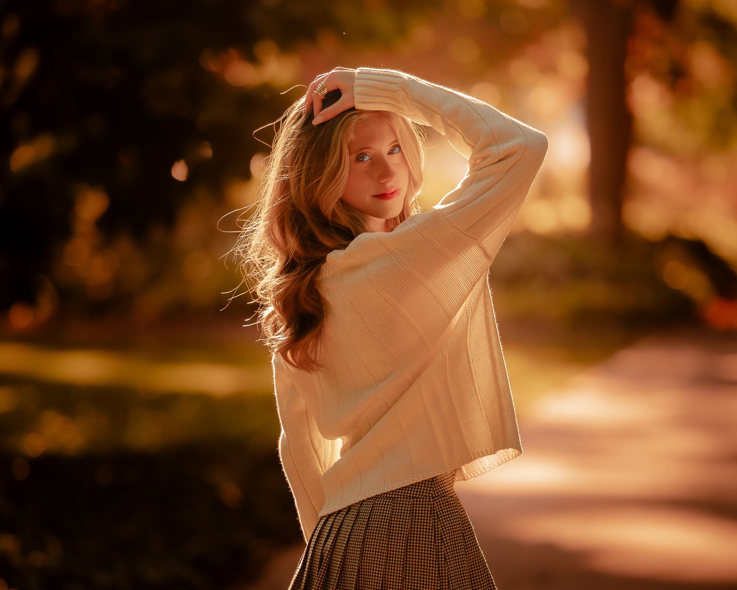 Person in casual outfit dancing in park during sunset with warm golden lighting.