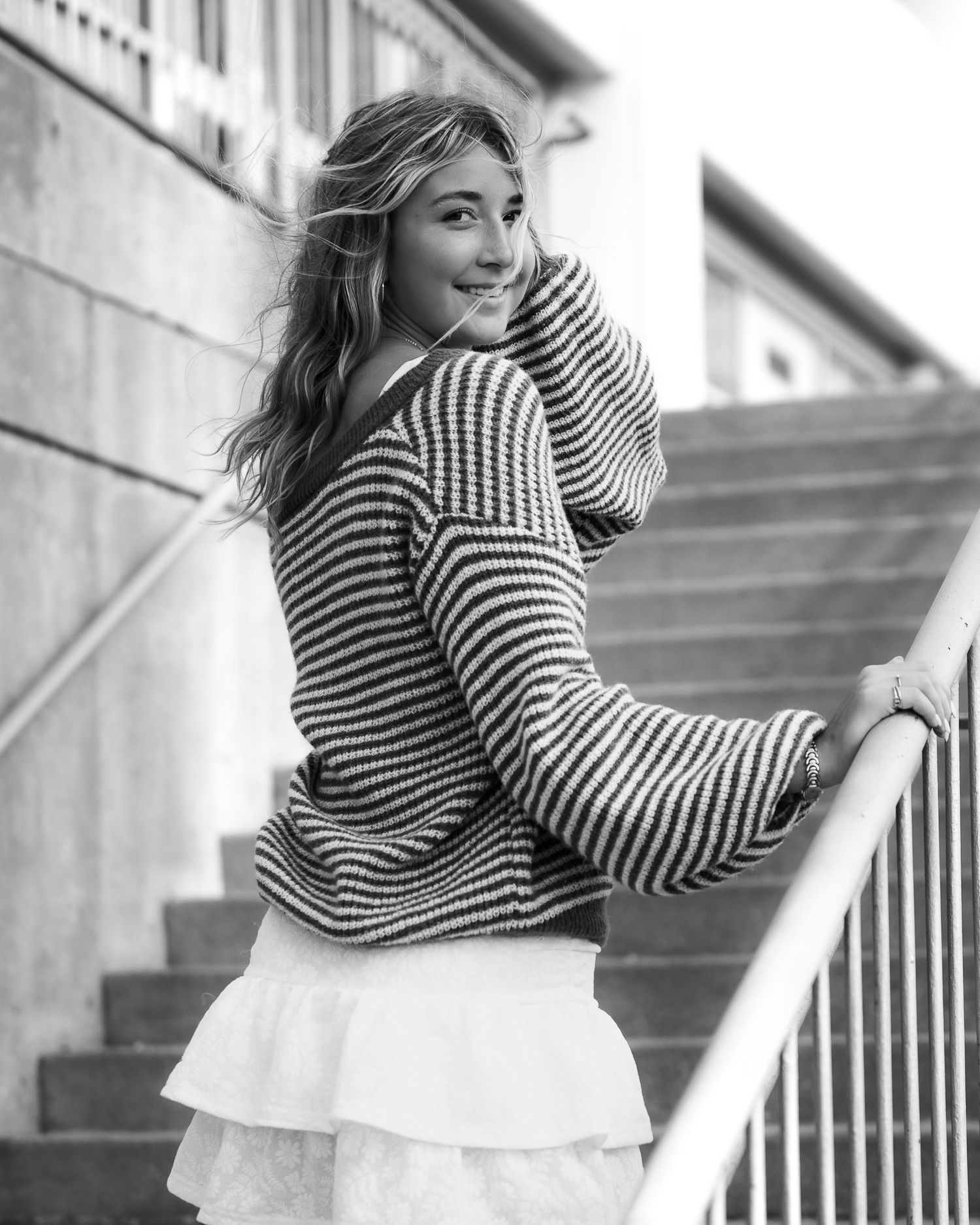 Woman in striped sweater poses on staircase in black and white photo sequence.