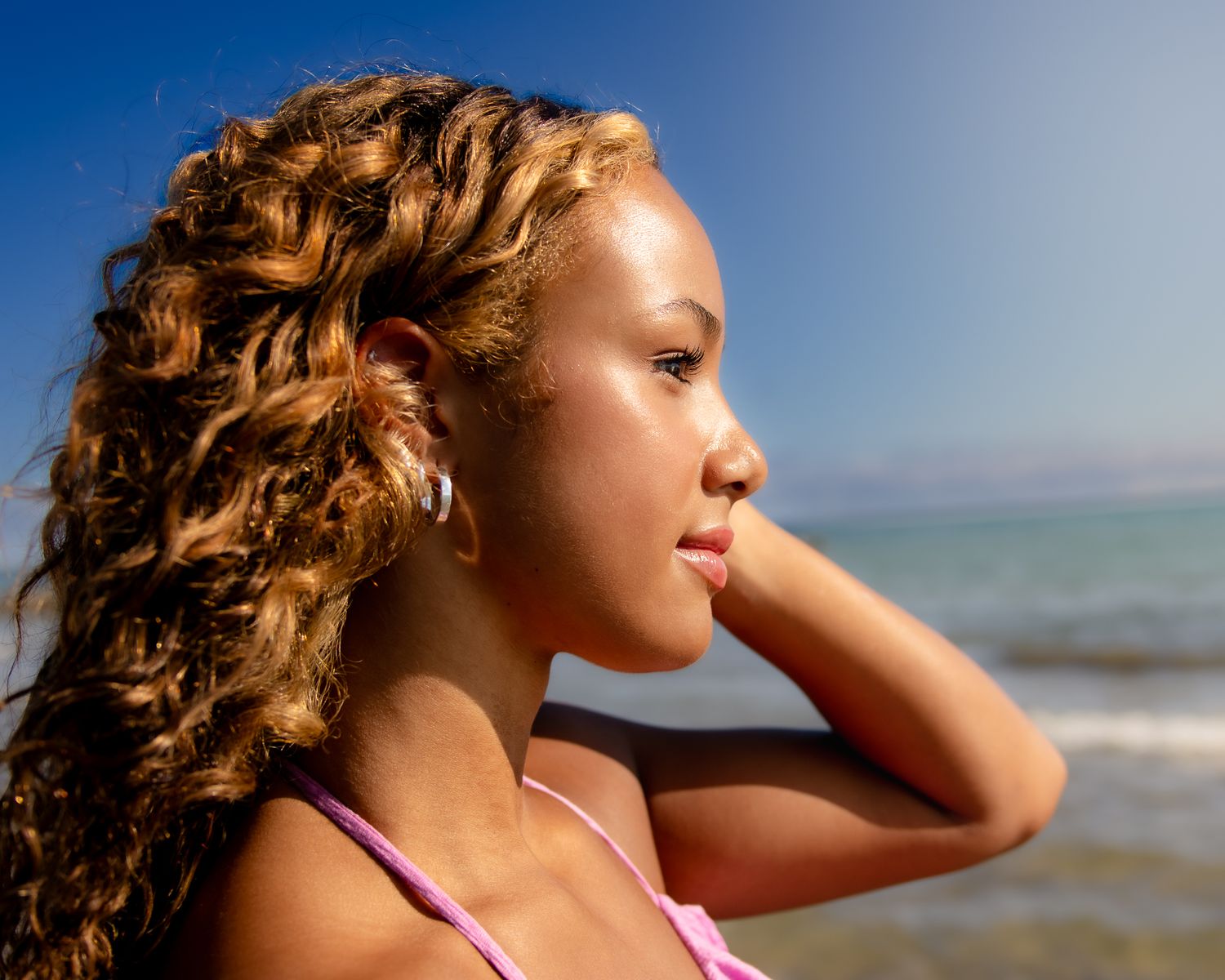 Profile portrait at the beach against blue sky and ocean.