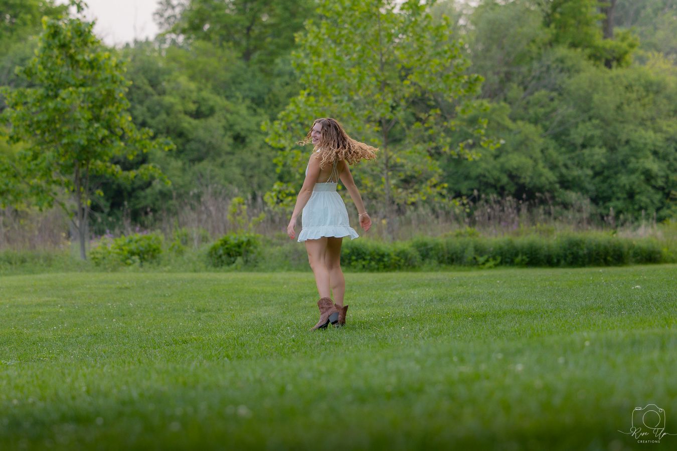 A figure walks through a lush green field during a summer photoshoot.
