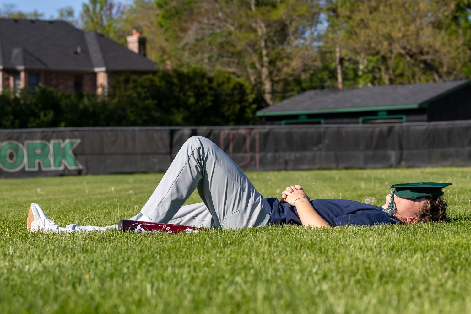 Students relaxing on grass during graduation day celebrations.