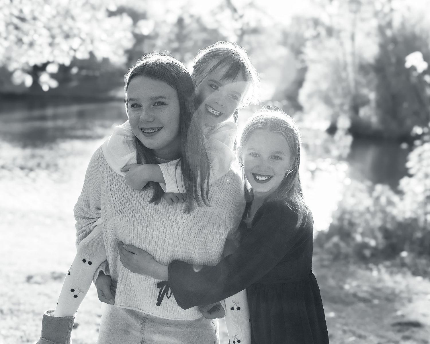 Black and white portrait of three people embracing outdoors.