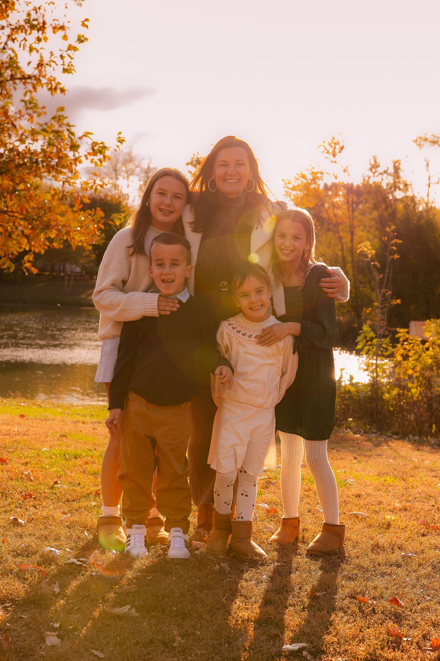 Family group poses together during golden hour in autumn setting.