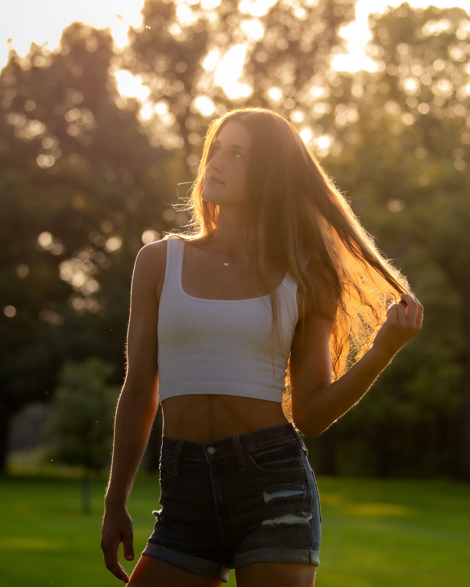 Person in casual summer outfit walking through park during golden hour sunset.