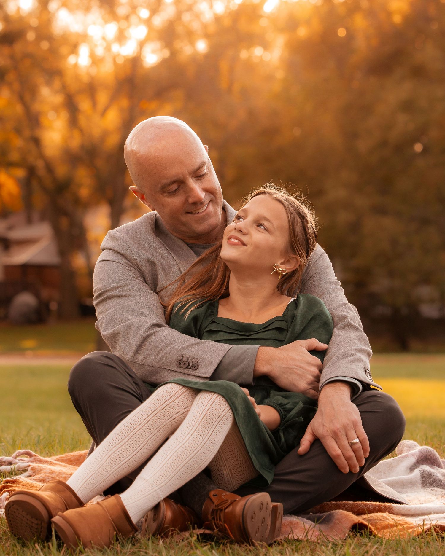 Romantic couple lounges on blanket in park during autumn sunset.