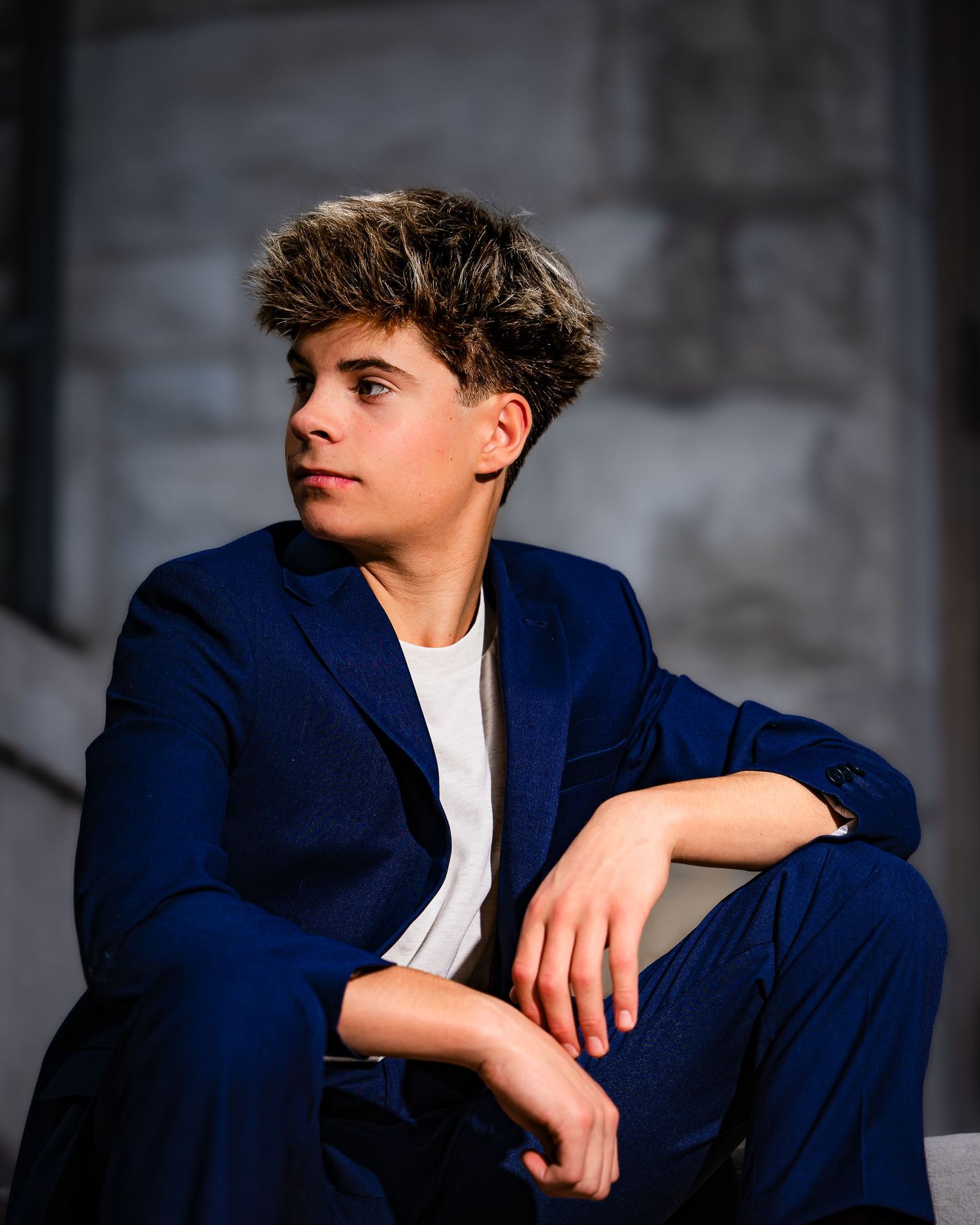 Portrait series of someone in a navy blazer and white shirt against a dark background.