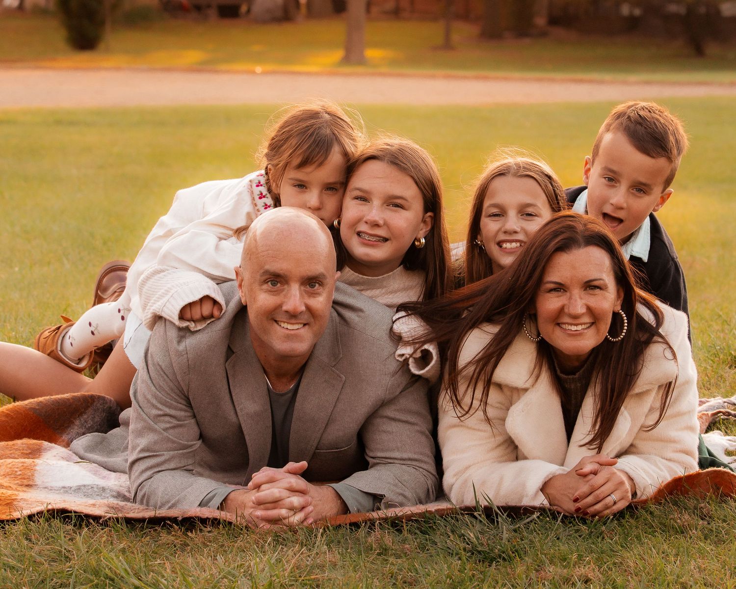 Family members pose together lying on grass during fall photo session.