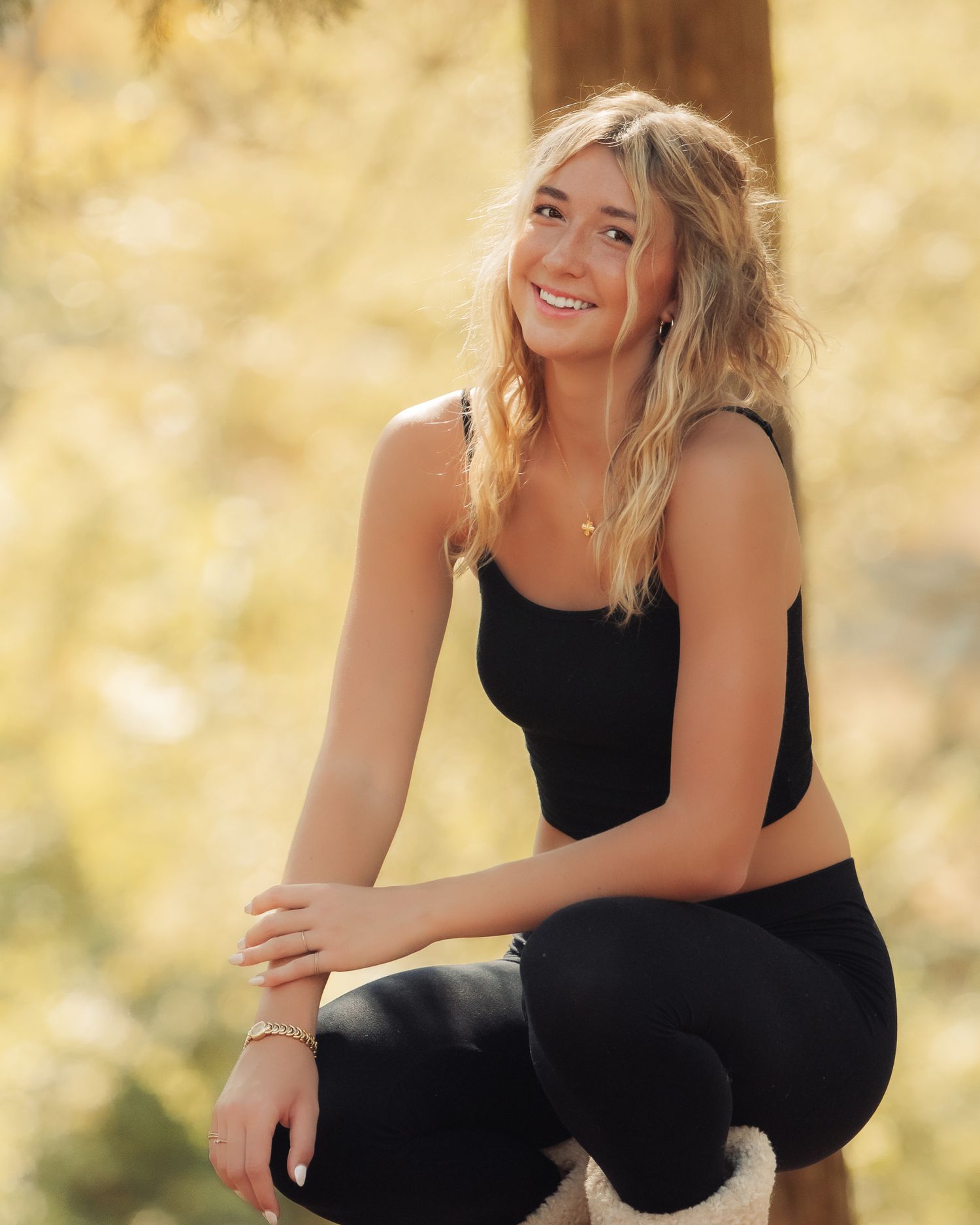 Person in black outfit poses on outdoor steps during golden hour.