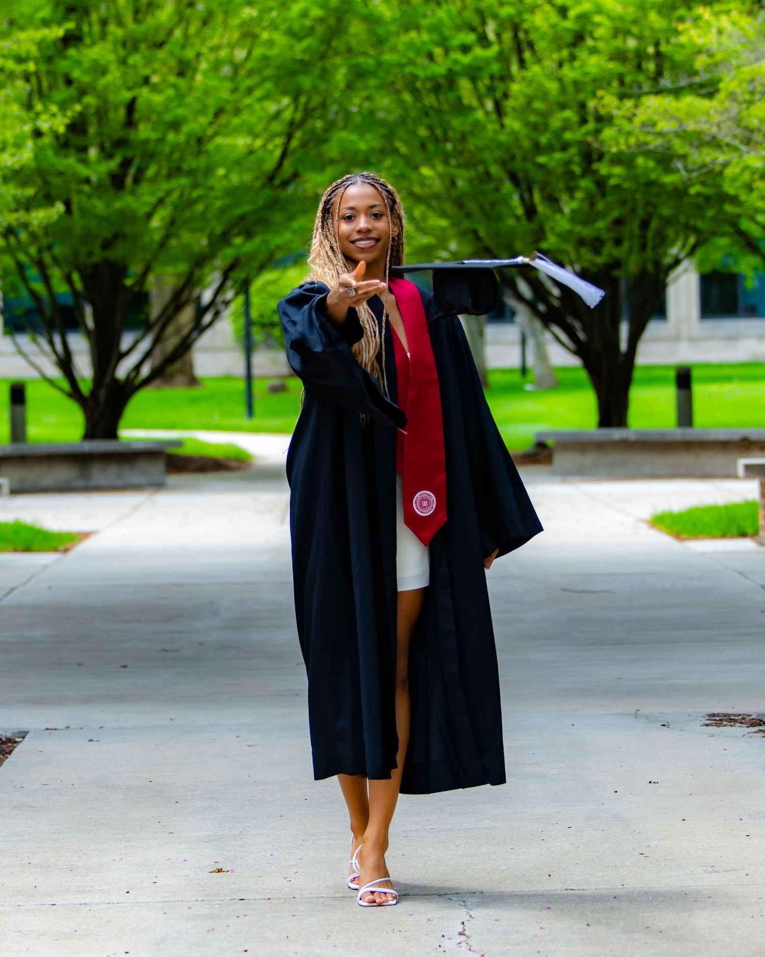 Cap and gown walking forward with hat extended