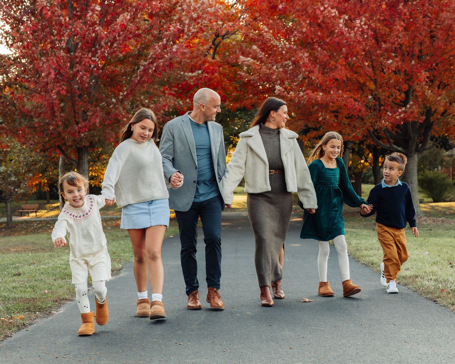 Group walking together beneath vibrant red autumn trees on path.