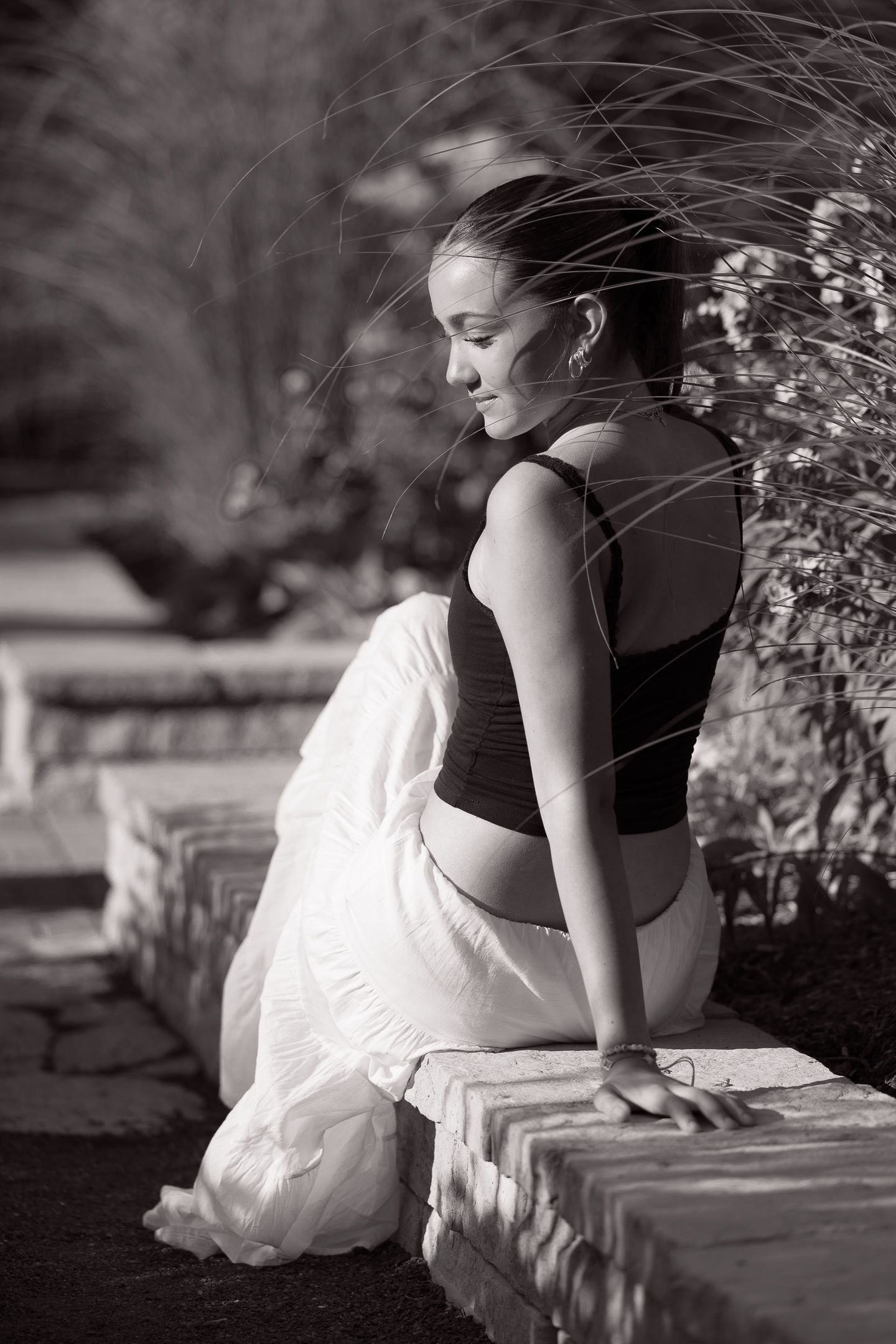 Black and white photo series showing someone in casual attire sitting on stone wall.