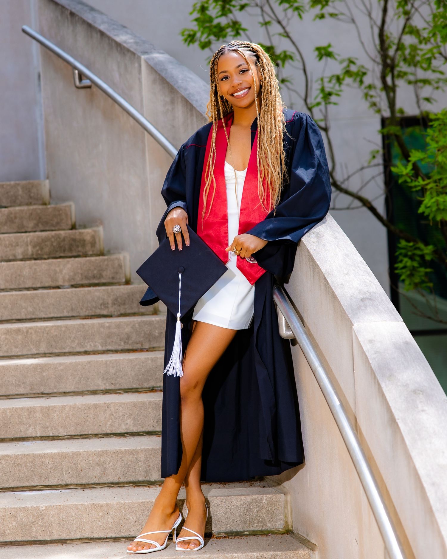 Person in navy blazer and red top sitting elegantly on concrete stairs.