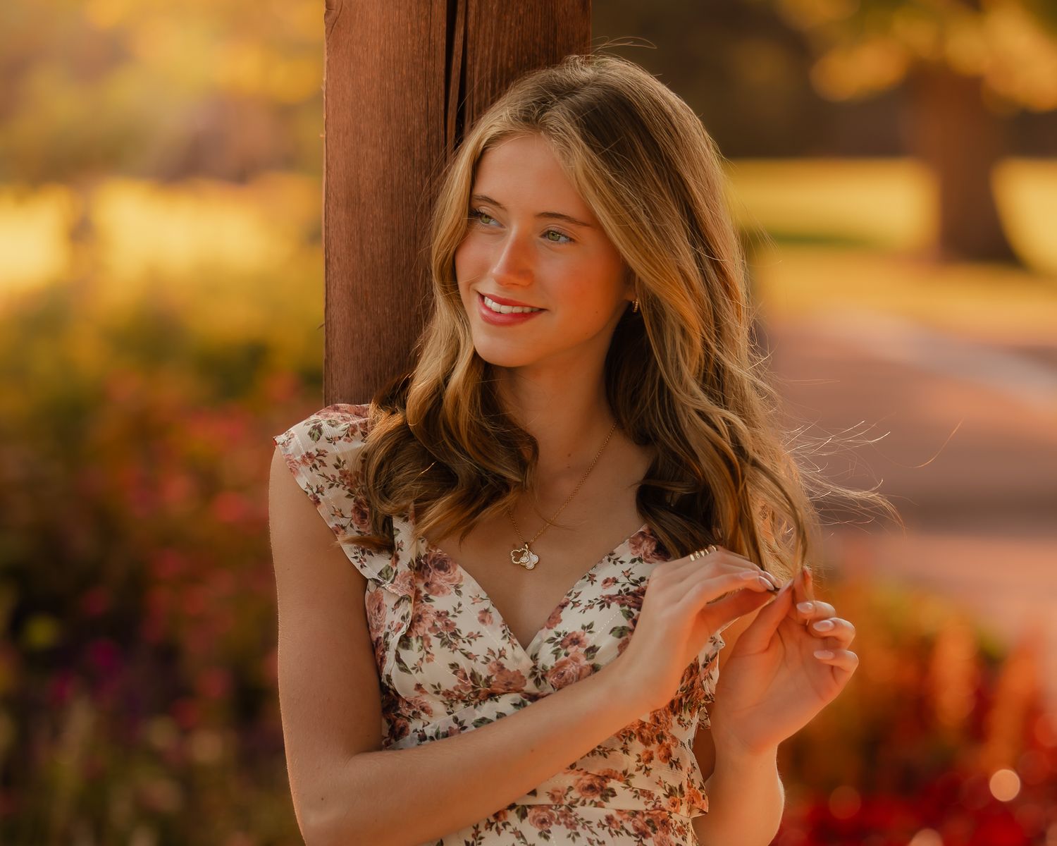 Person in floral dress twirling during golden hour with autumn foliage in background.