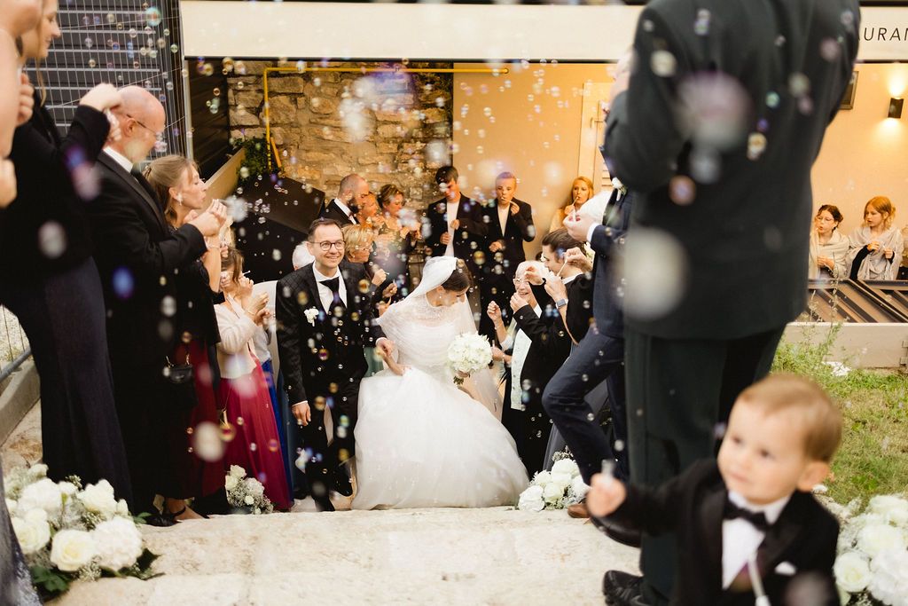 Newlyweds celebrating with confetti and bubbles as guests cheer on the steps after the ceremony.