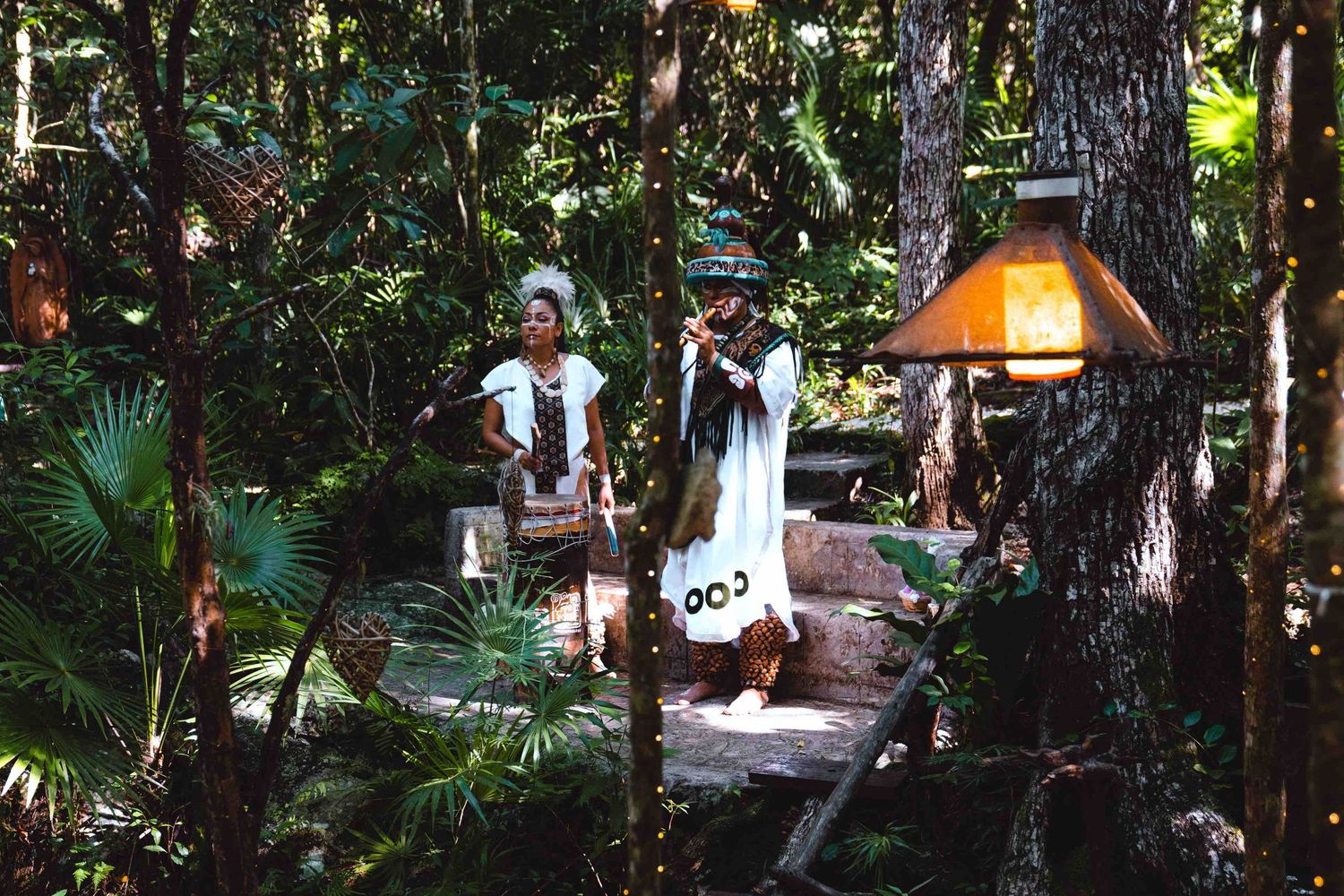 Traditional Mayan musicians performing in a lush tropical jungle setting during a wedding ceremony.