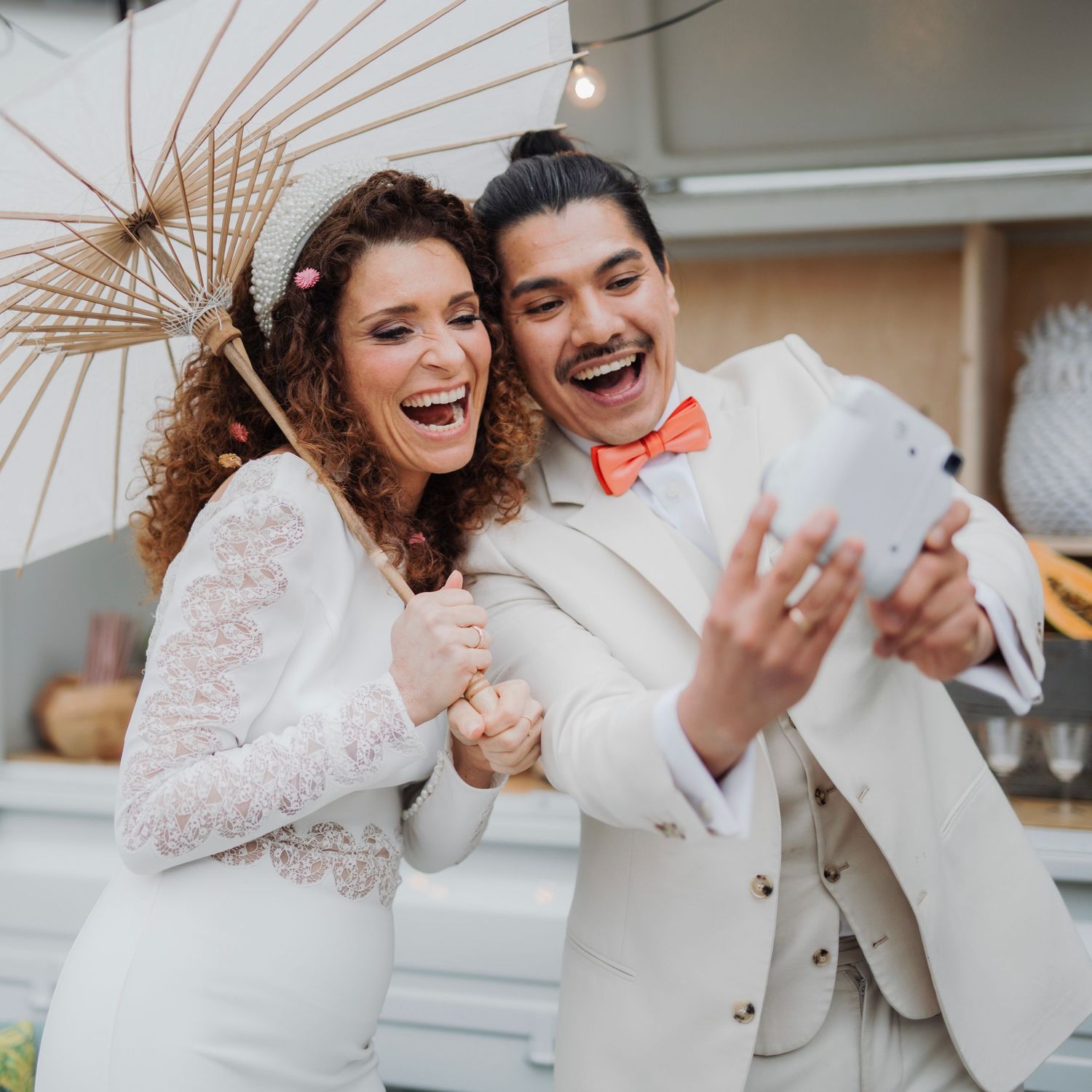Happy couple in wedding attire laughing while taking a selfie outdoors.