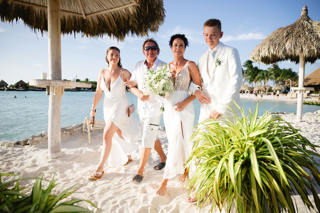 Wedding party of four posing and walking on a white sandy tropical beach.