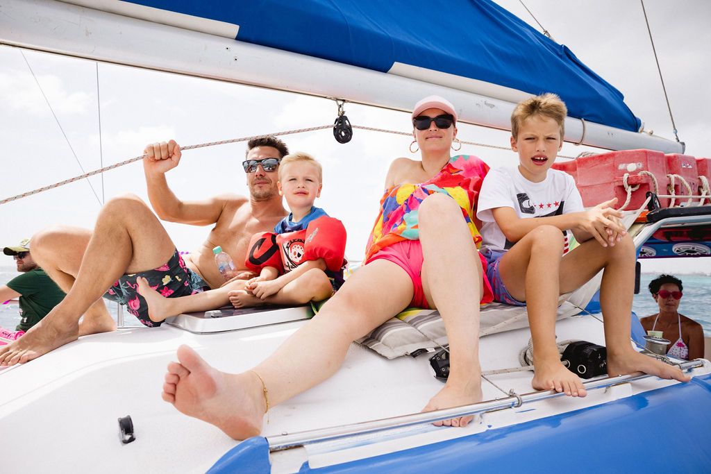 A cheerful family relaxes on the deck of a sailboat on a bright sunny day.