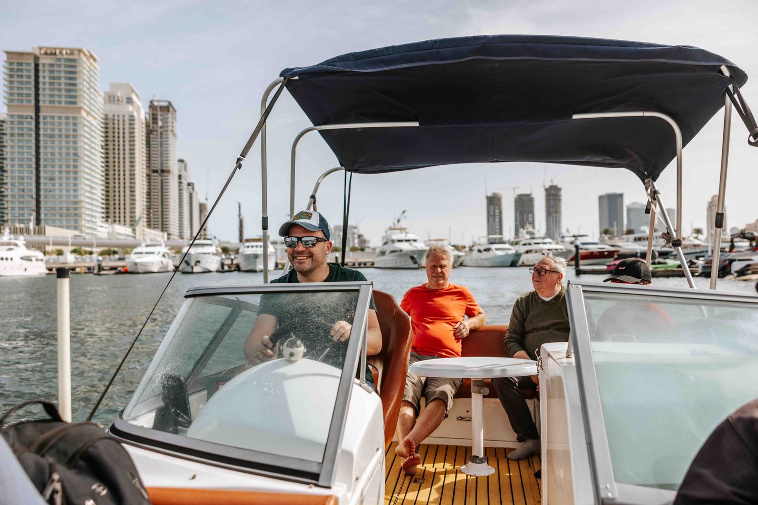 Group of people enjoying a boat ride in a marina with a city skyline backdrop.