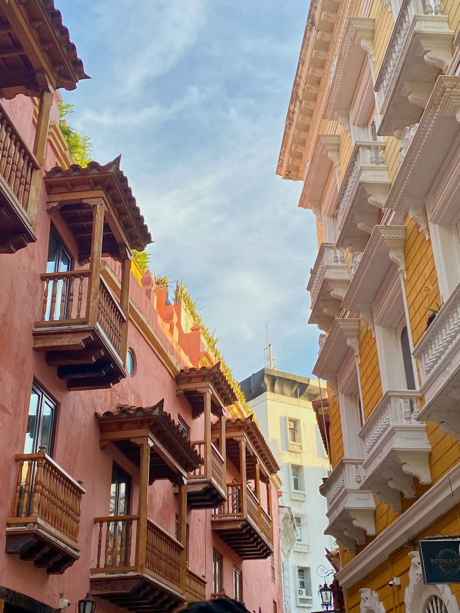 Colorful colonial architecture with wooden balconies lining a narrow street under a blue sky.