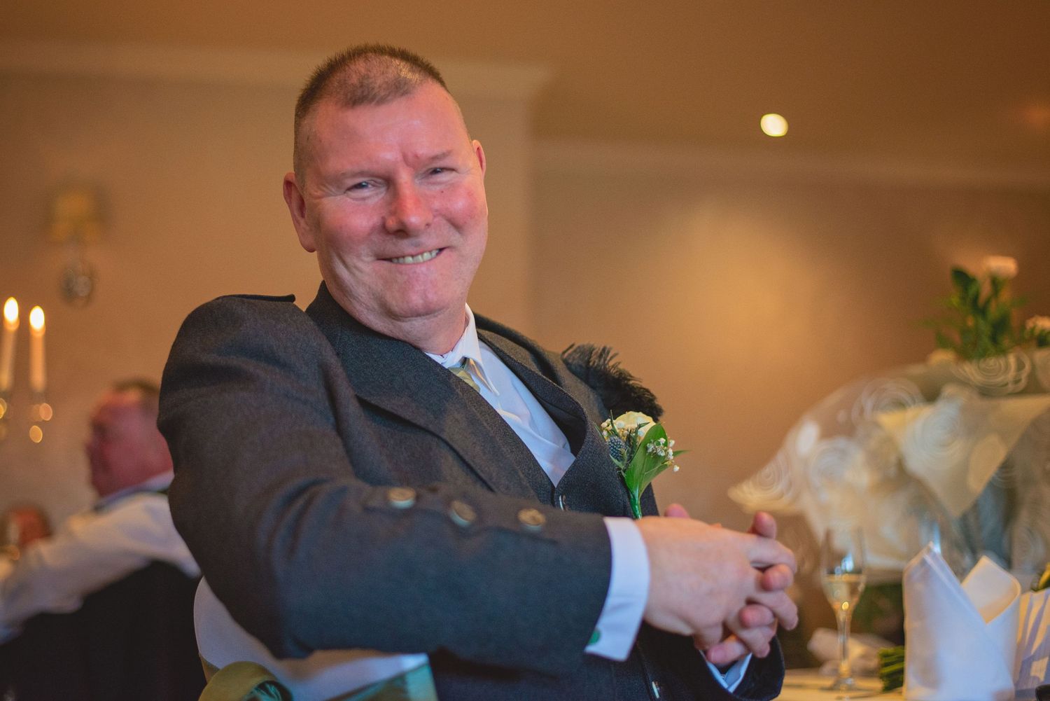 A guest at a wedding celebration wearing a dark suit with boutonniere.