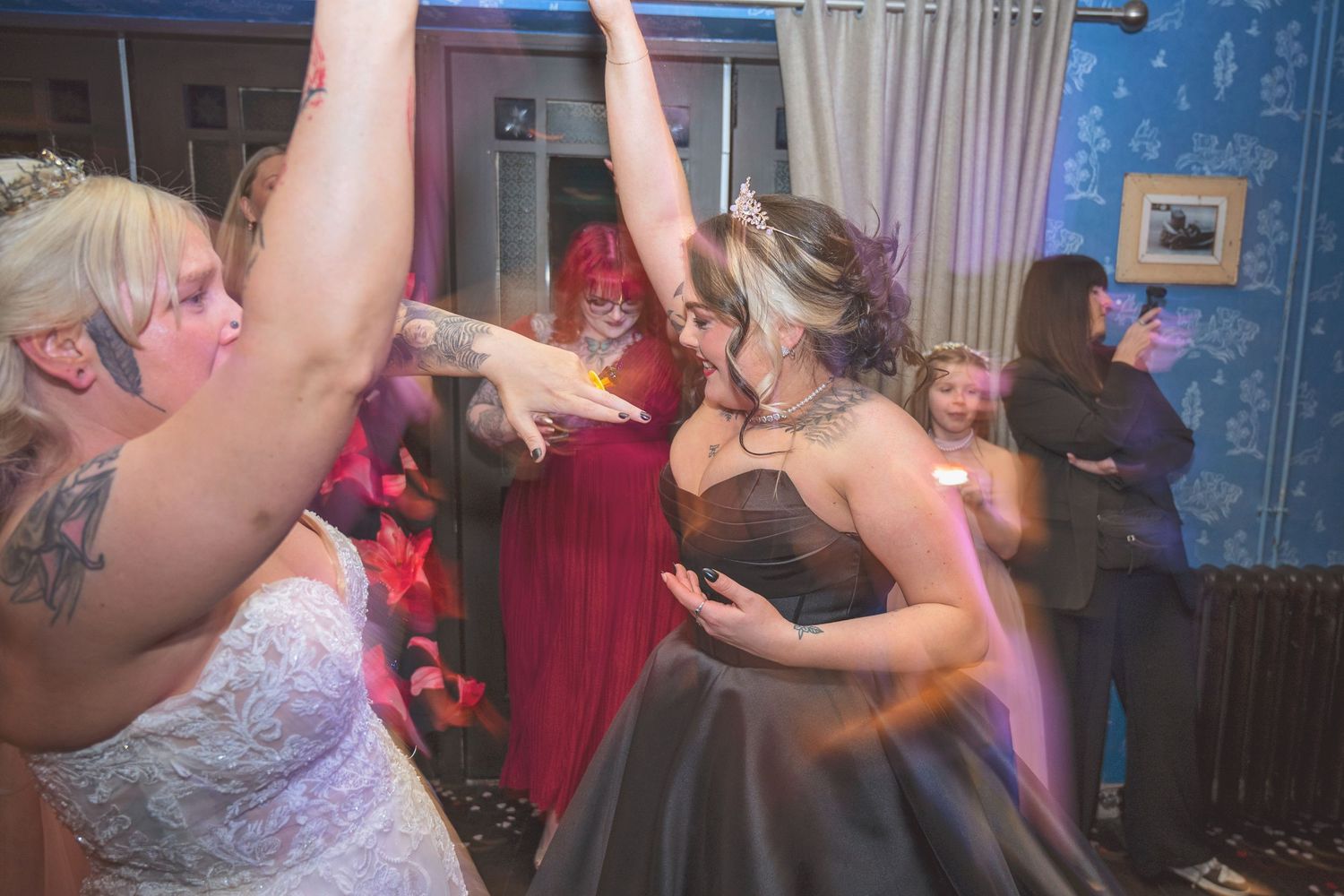 Bride in white gown and guests in formal attire dance energetically at lively wedding reception party.