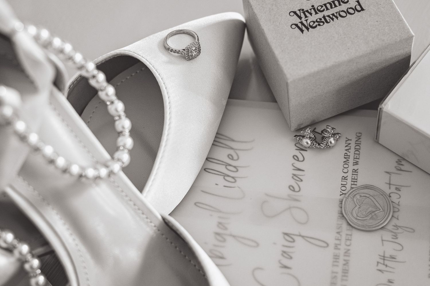 Wedding accessories including white shoes, pearl necklace, rings and invitation details.