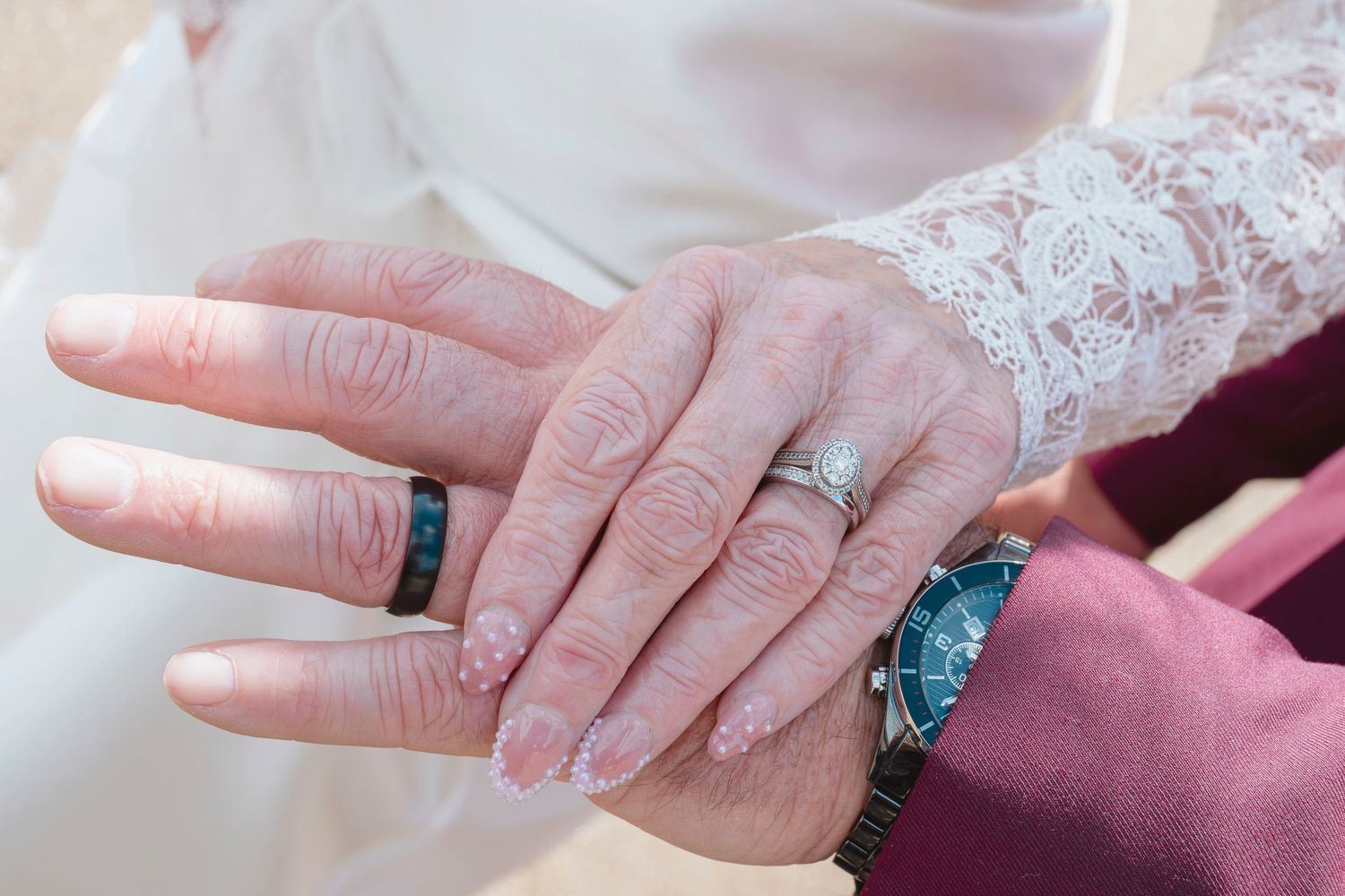 Close-up of newlyweds hands showing wedding rings, bride wearing diamond ring and groom wearing black band.