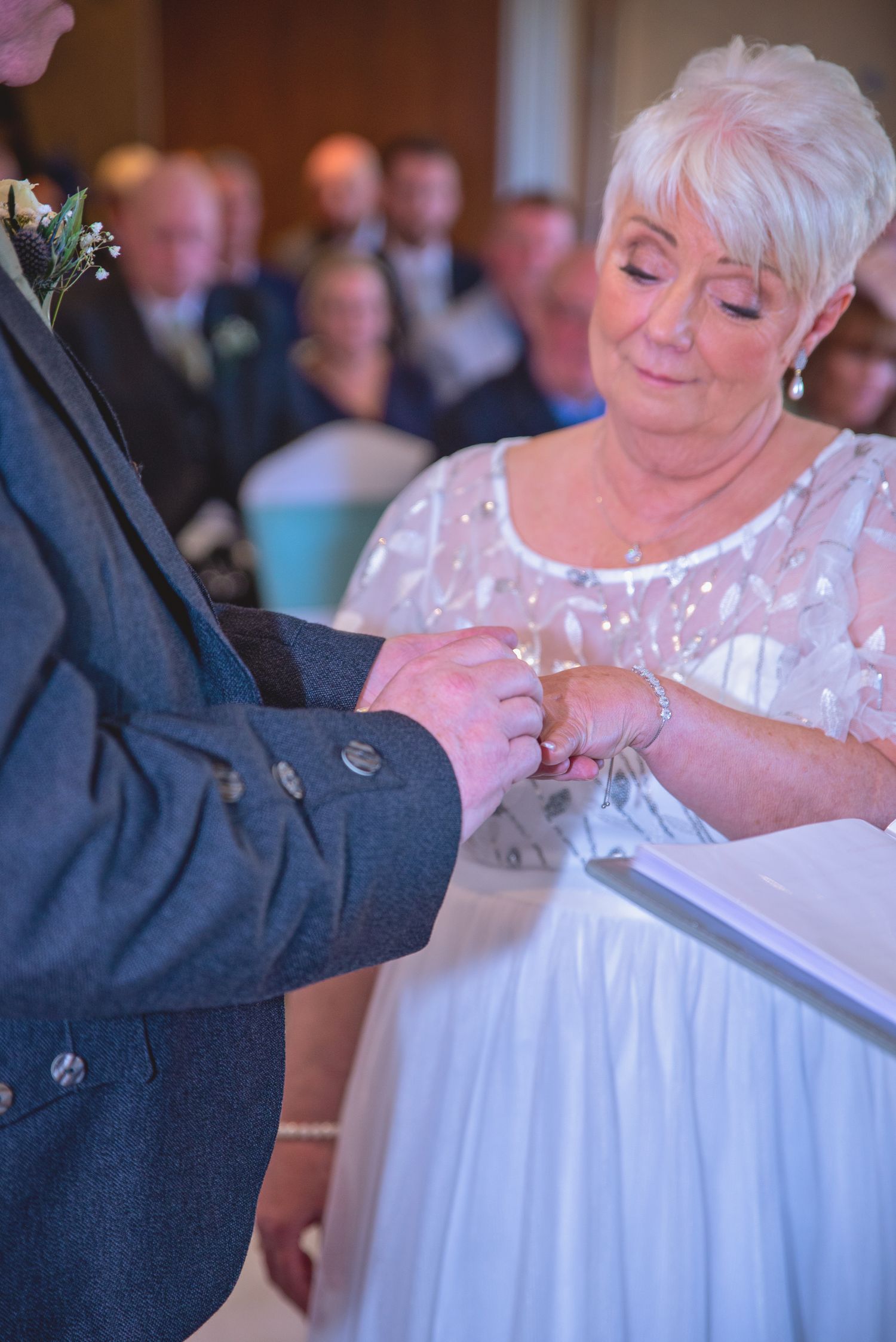 Close-up of hands exchanging wedding rings during an emotional ceremony moment.