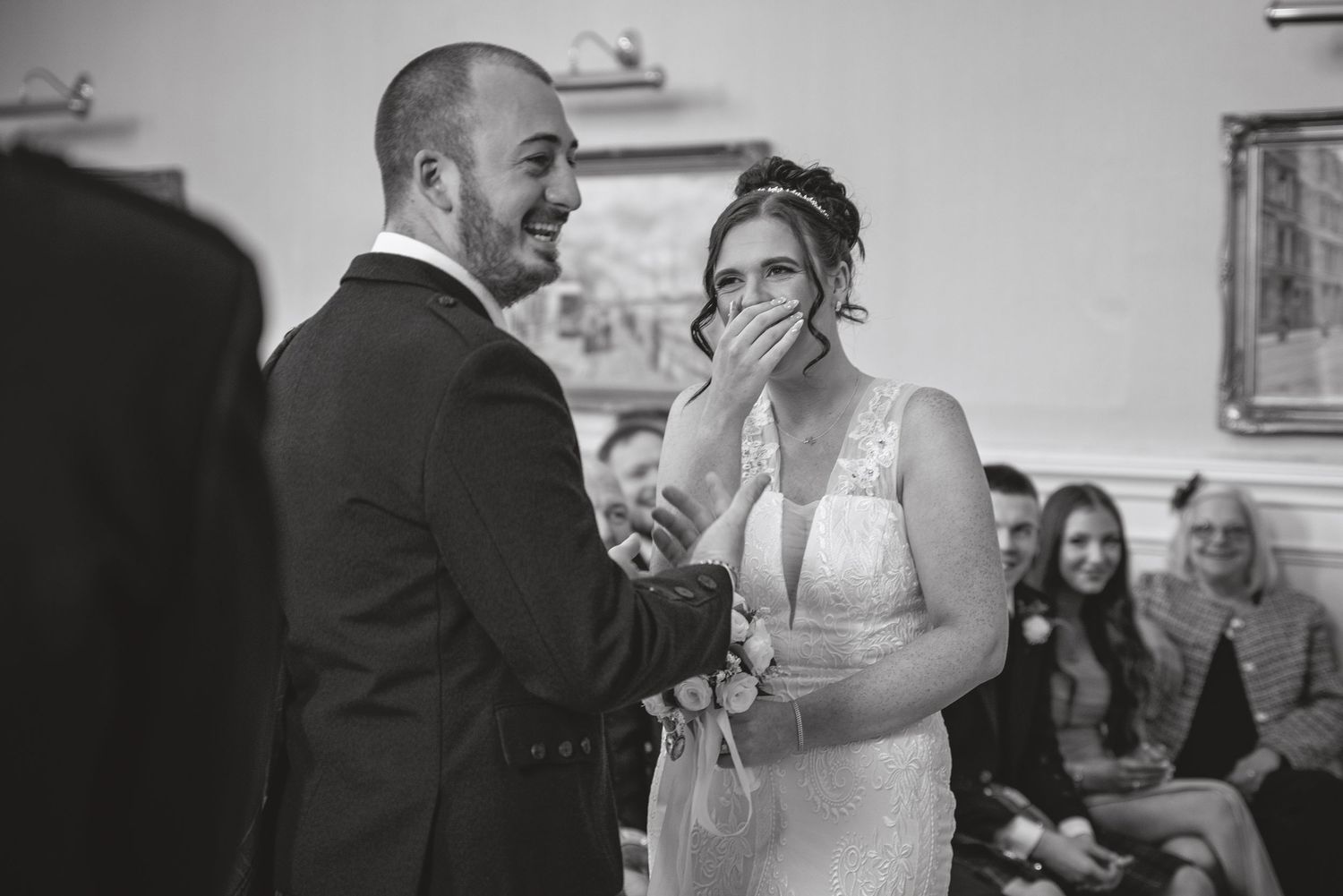 Black and white candid moment during wedding ceremony with emotional reactions.