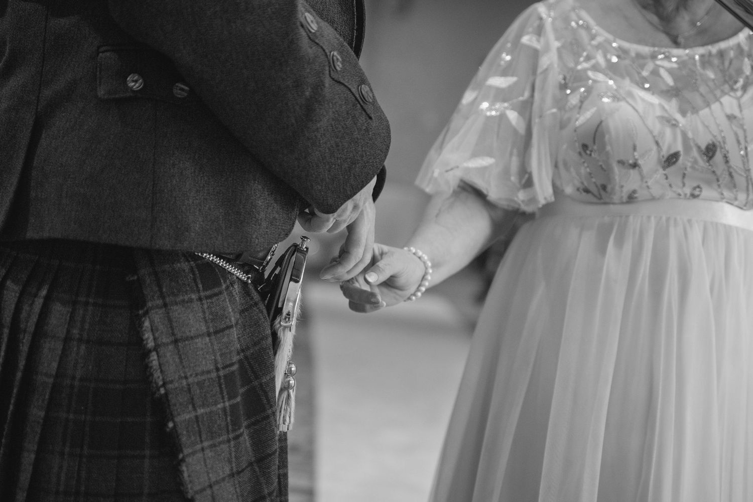 Close-up black and white shot of hands exchanging rings during a Scottish wedding ceremony.