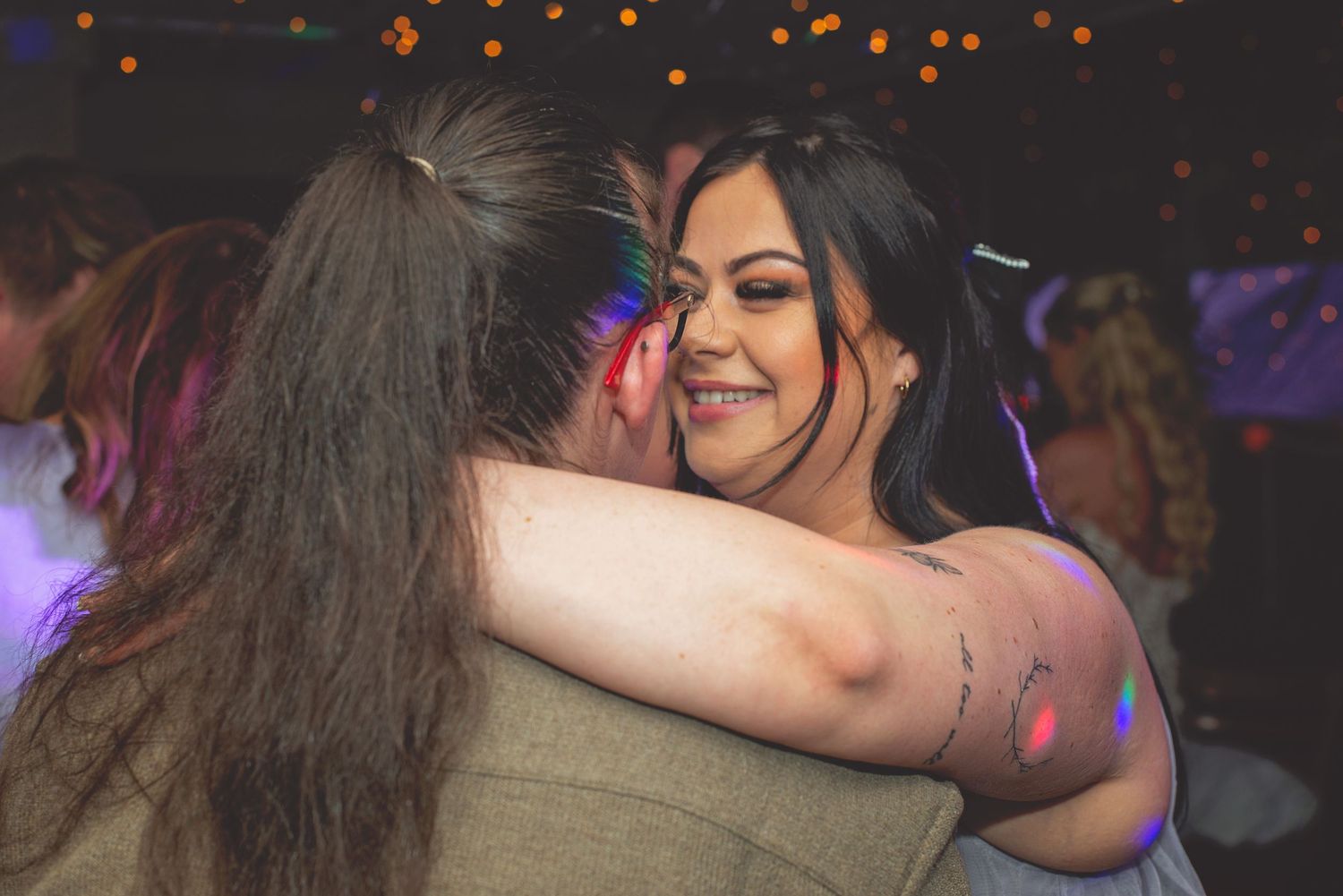 Wedding reception dance floor filled with celebrating guests under orange lights.