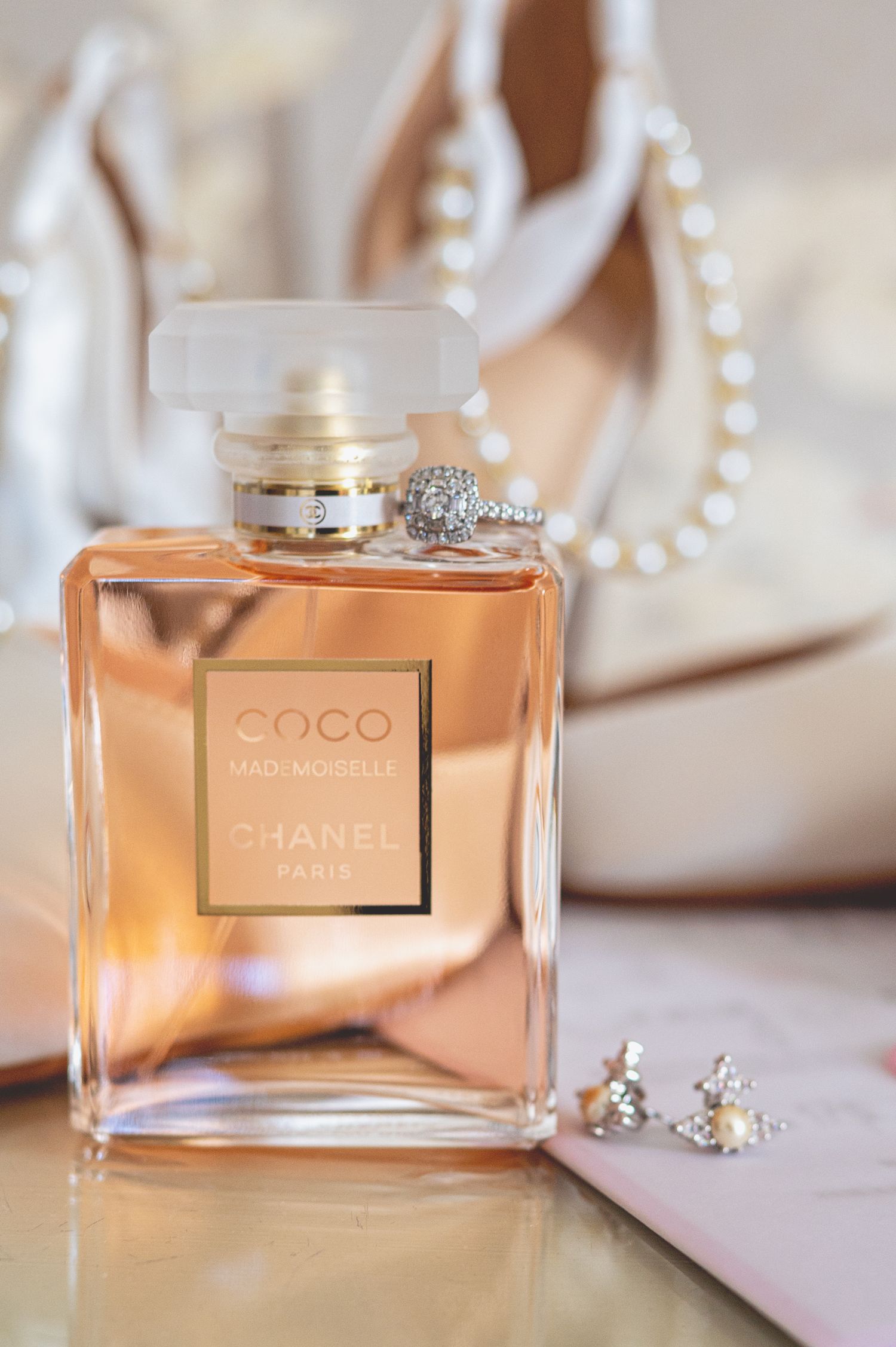 Chanel Coco Mademoiselle perfume bottle with wedding jewelry and pearl accessories.