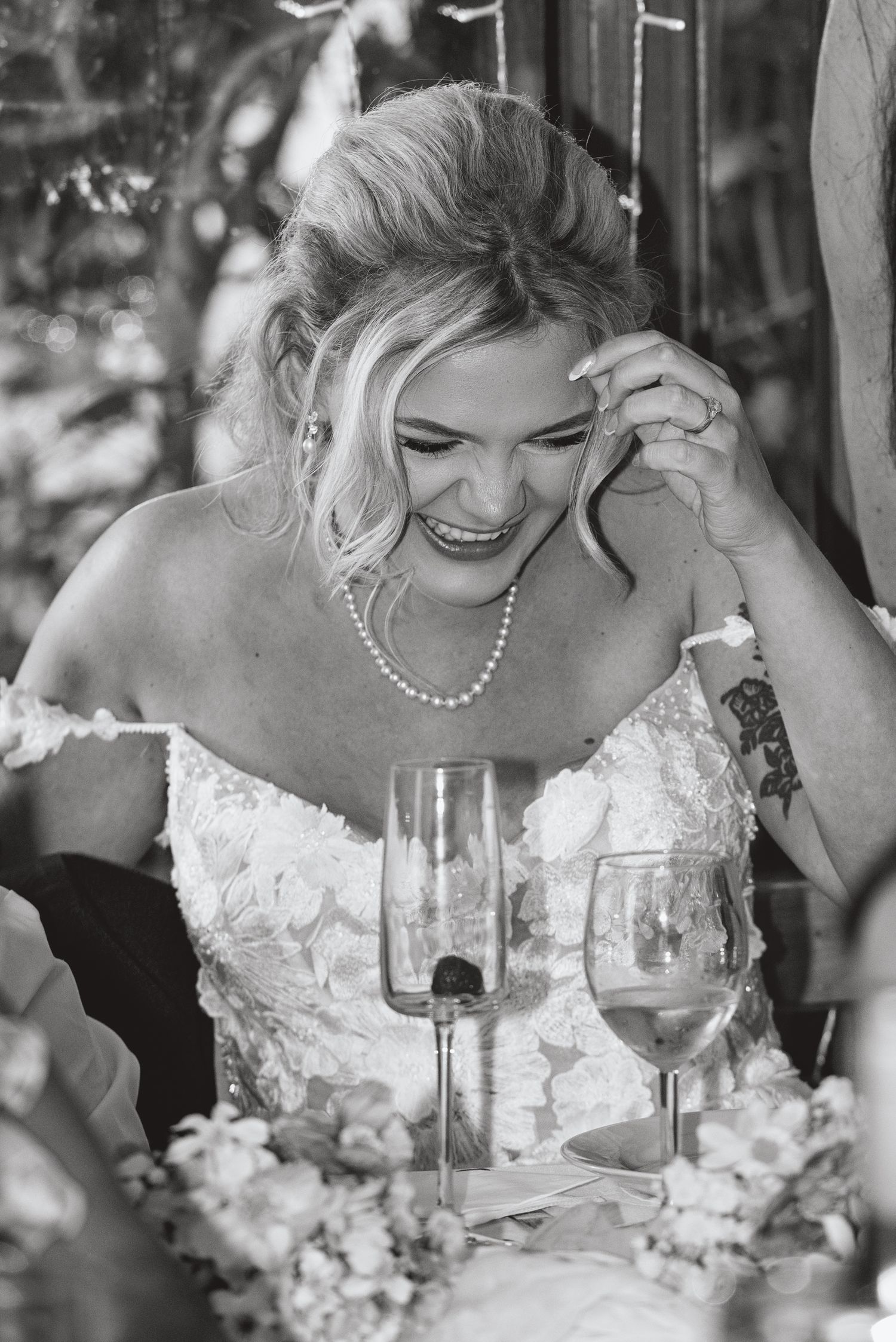 A joyful moment captured during a wedding reception with wine glasses and floral decorations.