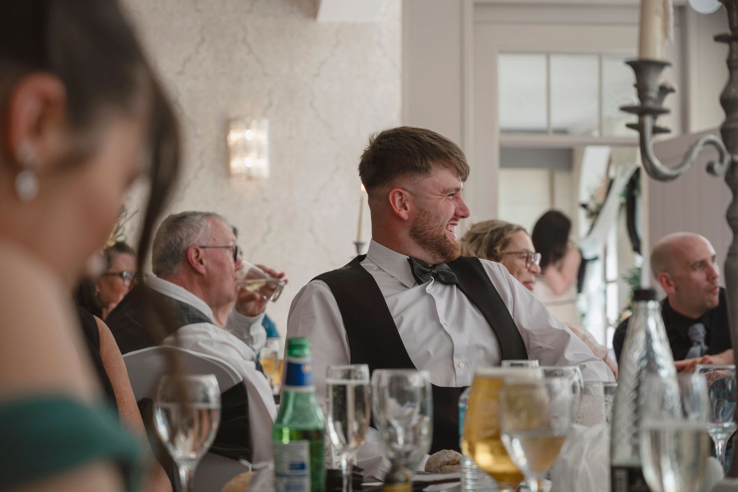 Guests seated at elegantly set tables during a formal wedding reception in a decorated banquet hall.