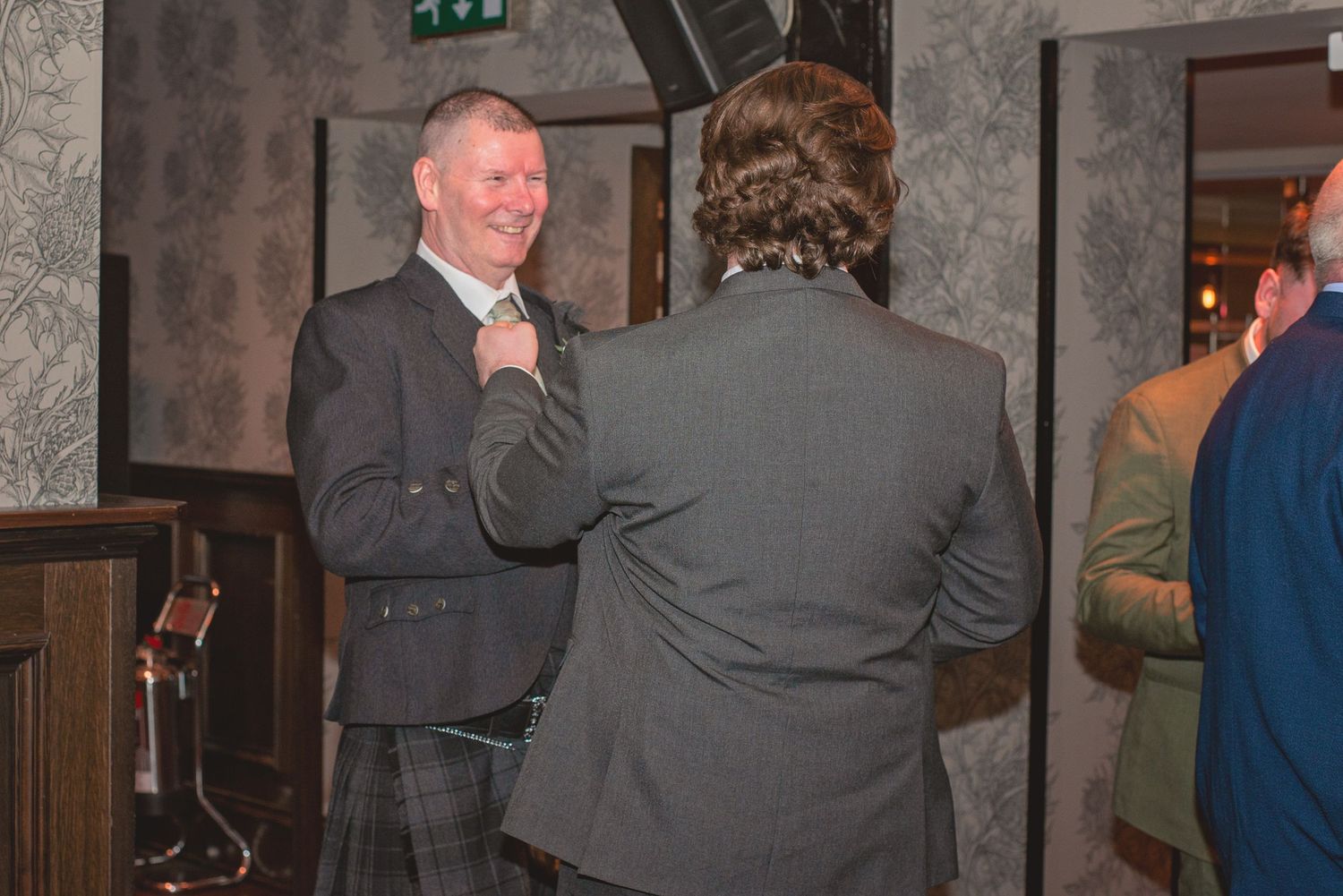 Guests mingling and dancing at an elegant wedding reception venue with ornate decor.