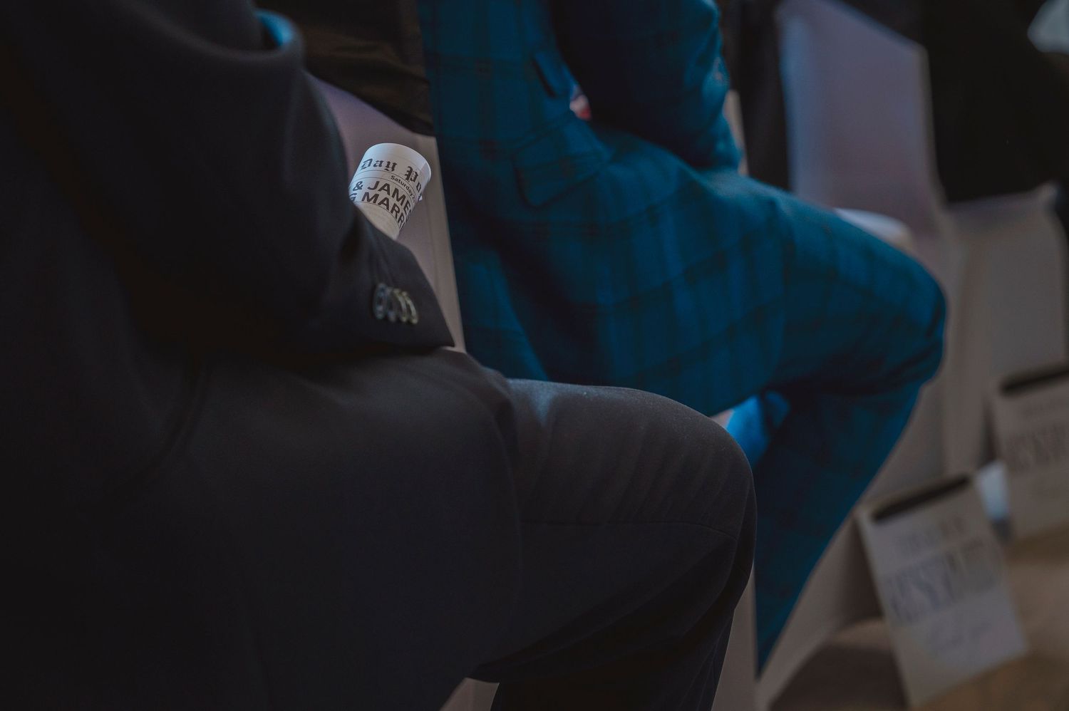 Person wearing a North Face cap and teal jacket seated in a dimly lit room.