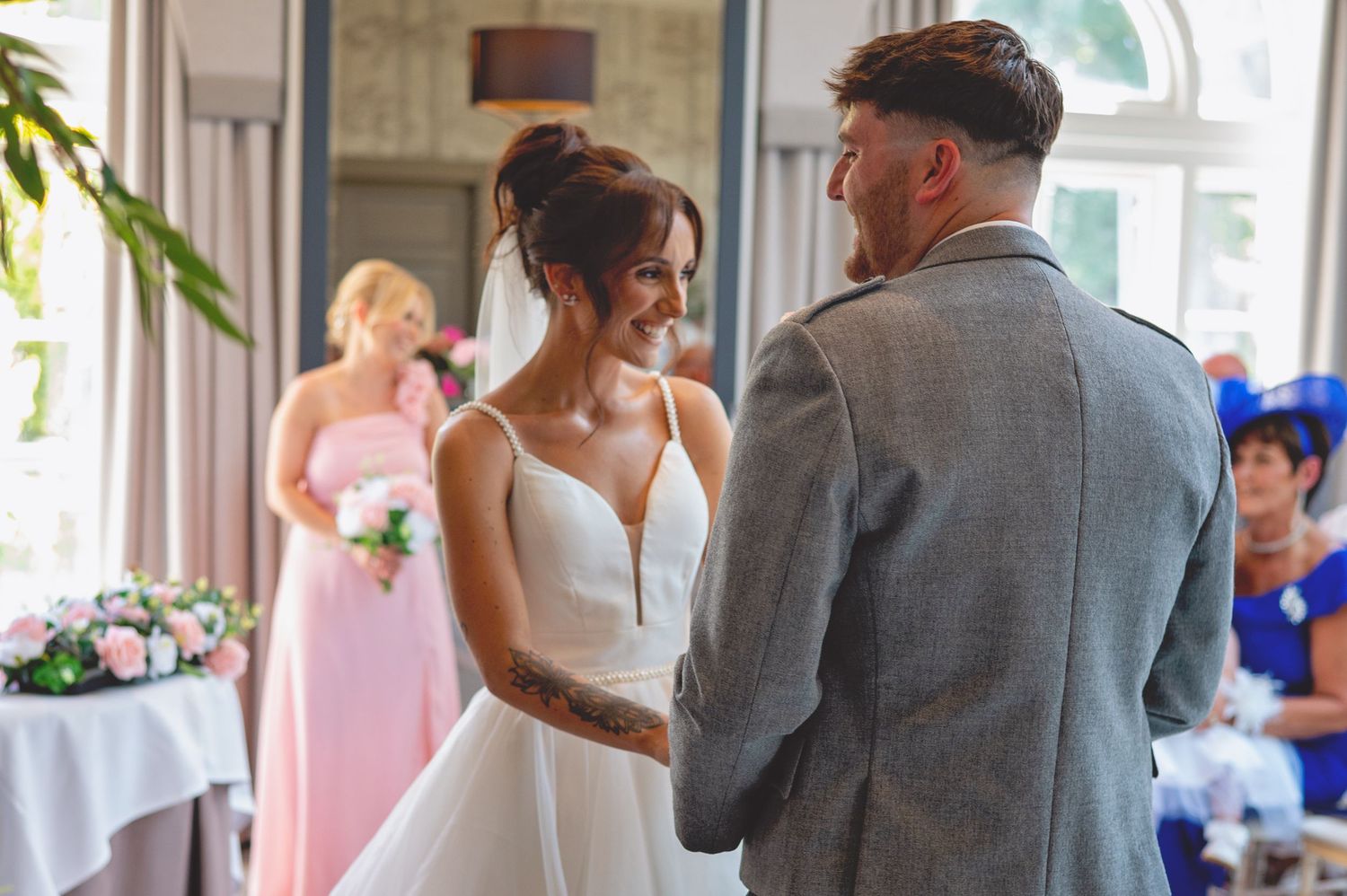 Wedding ceremony scene with floral decorations and guests in attendance.