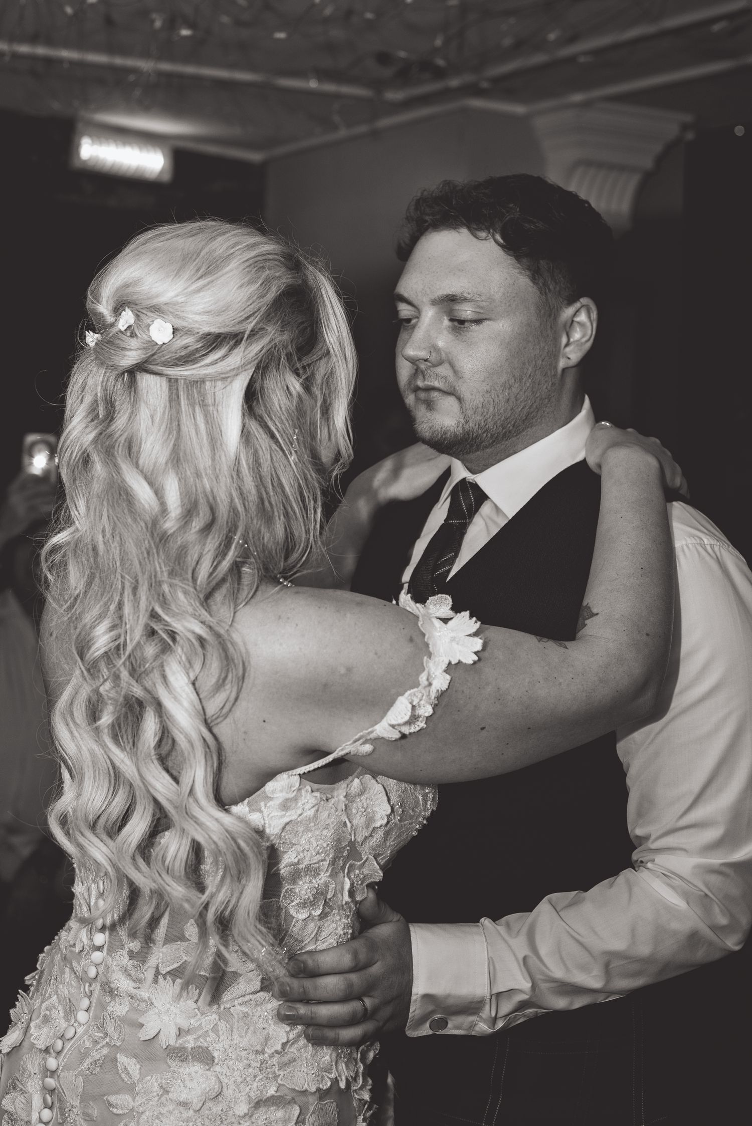 Couple shares intimate dance moment at dimly lit wedding reception.