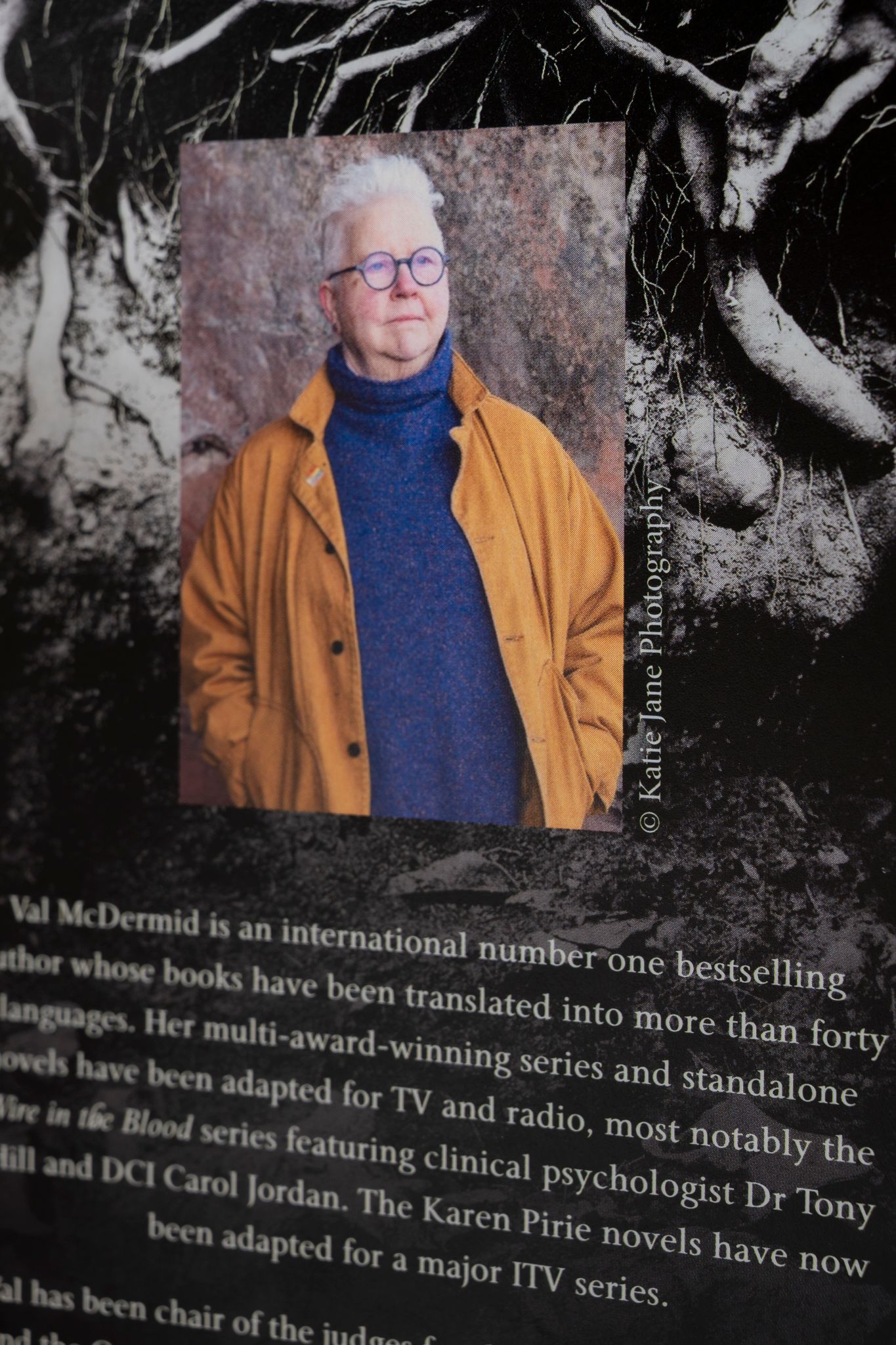 Val McDermid, bestselling crime author, poses in yellow jacket and blue sweater at a literary event display.