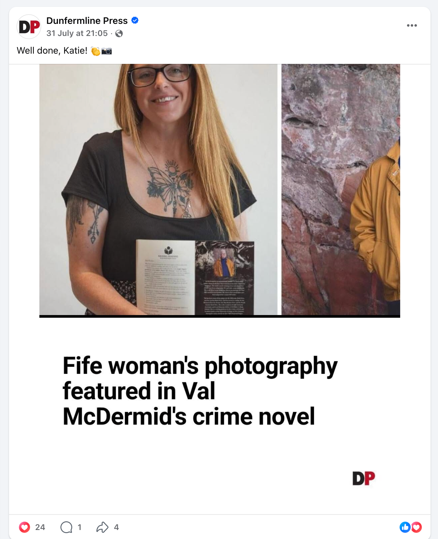 Fife woman proudly holds framed photography featured in Val McDermid crime novel, showcasing tattoos and blonde hair.