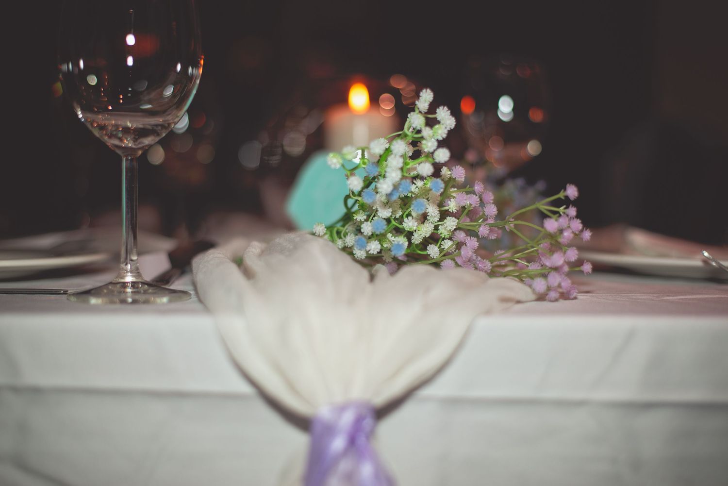 Elegant table settings with candlelight and floral decorations at a wedding reception.