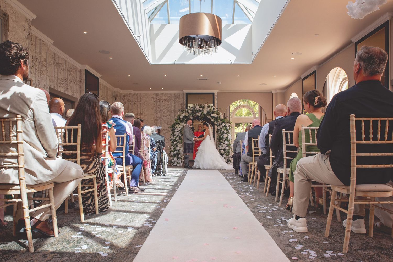 Interior view of an elegant wedding venue with skylight and rows of chairs.