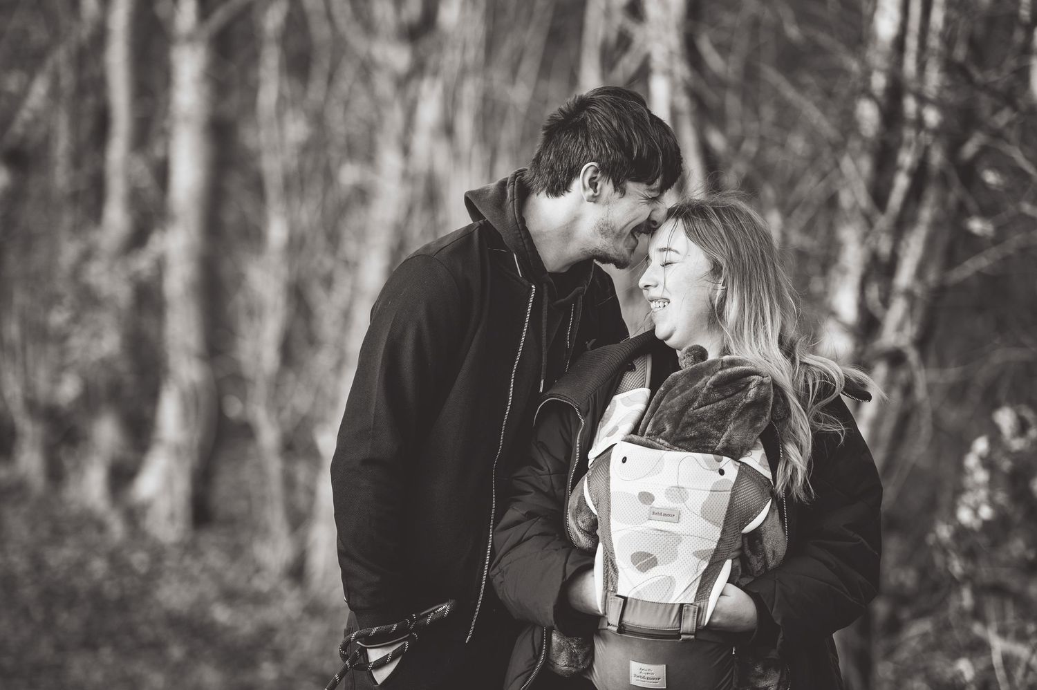 A romantic couple embraces in a misty forest setting during an engagement photo session.