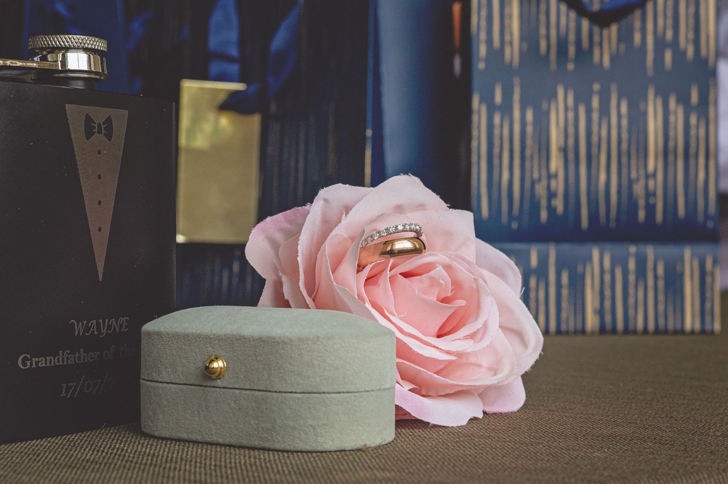Wedding decor featuring pink roses against a blue backdrop with metallic accents.