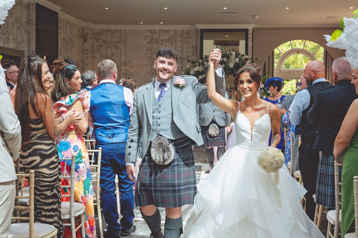 Wedding celebration in progress with guests mingling in decorated venue space.