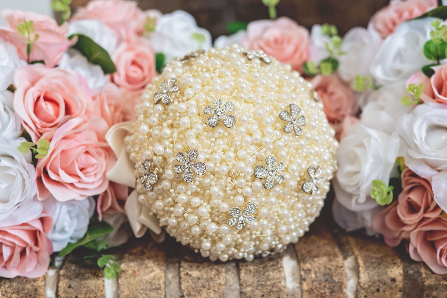 Delicate pink roses and pearl decorations arranged in an elegant wedding display.
